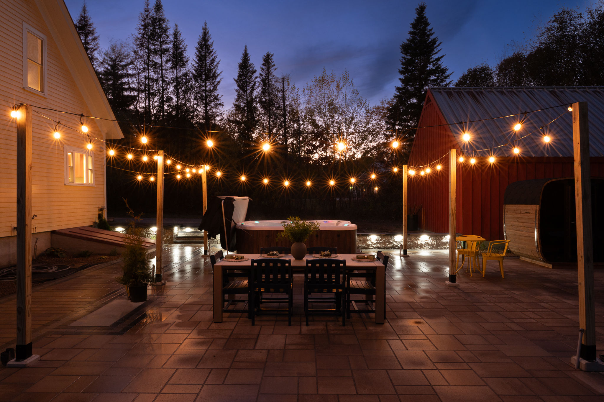 Lit patio with hot tub and outdoor dining at dusk