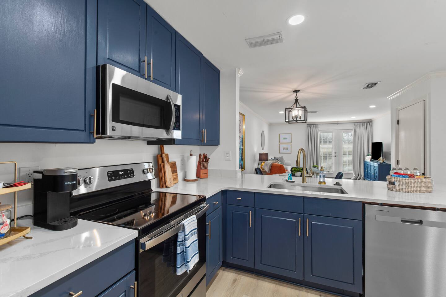 A complete kitchen with a Keurig, microwave, electric range, dishwasher and refrigerator.