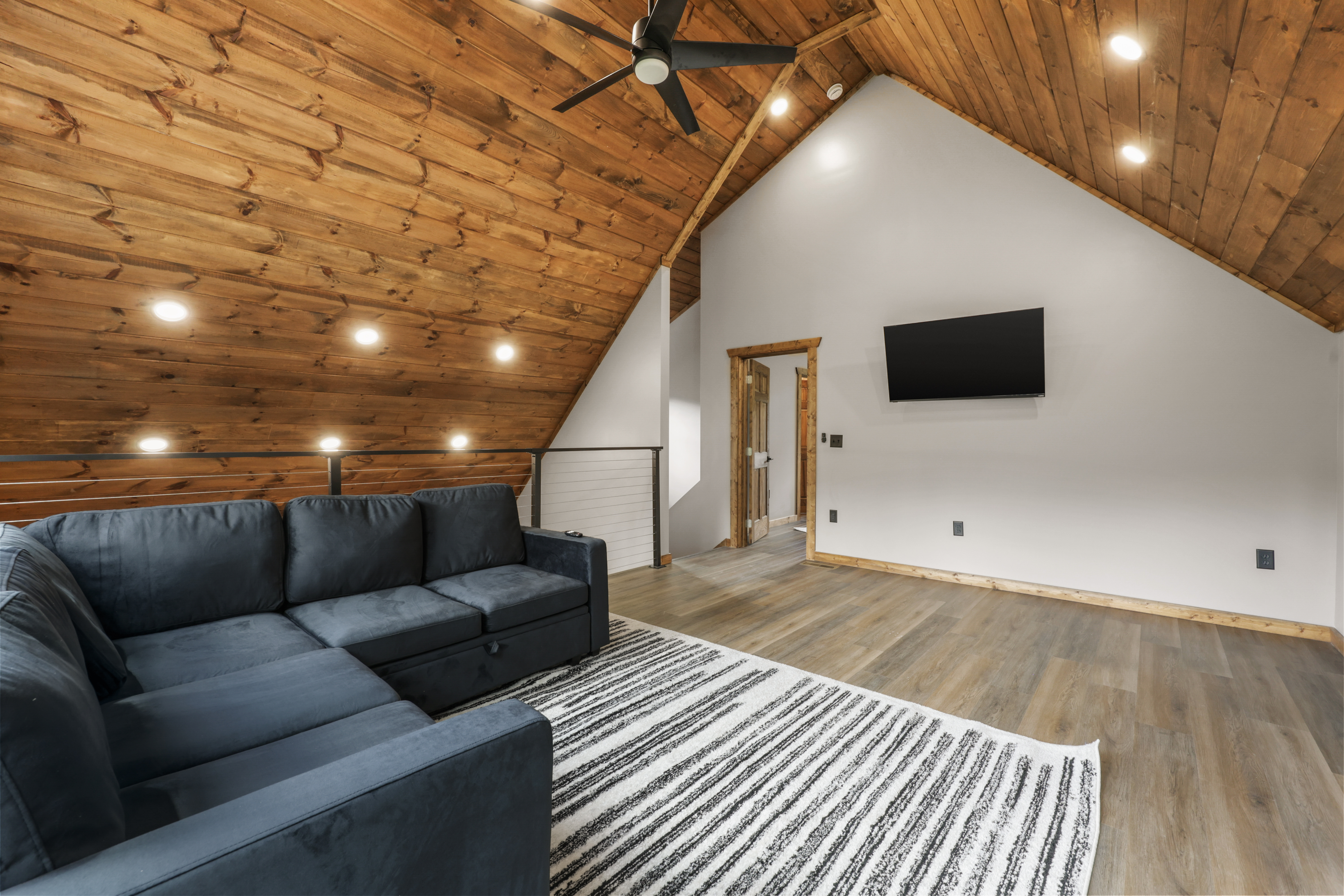 Cozy loft lounge with vaulted wood ceilings, sectional, and TV