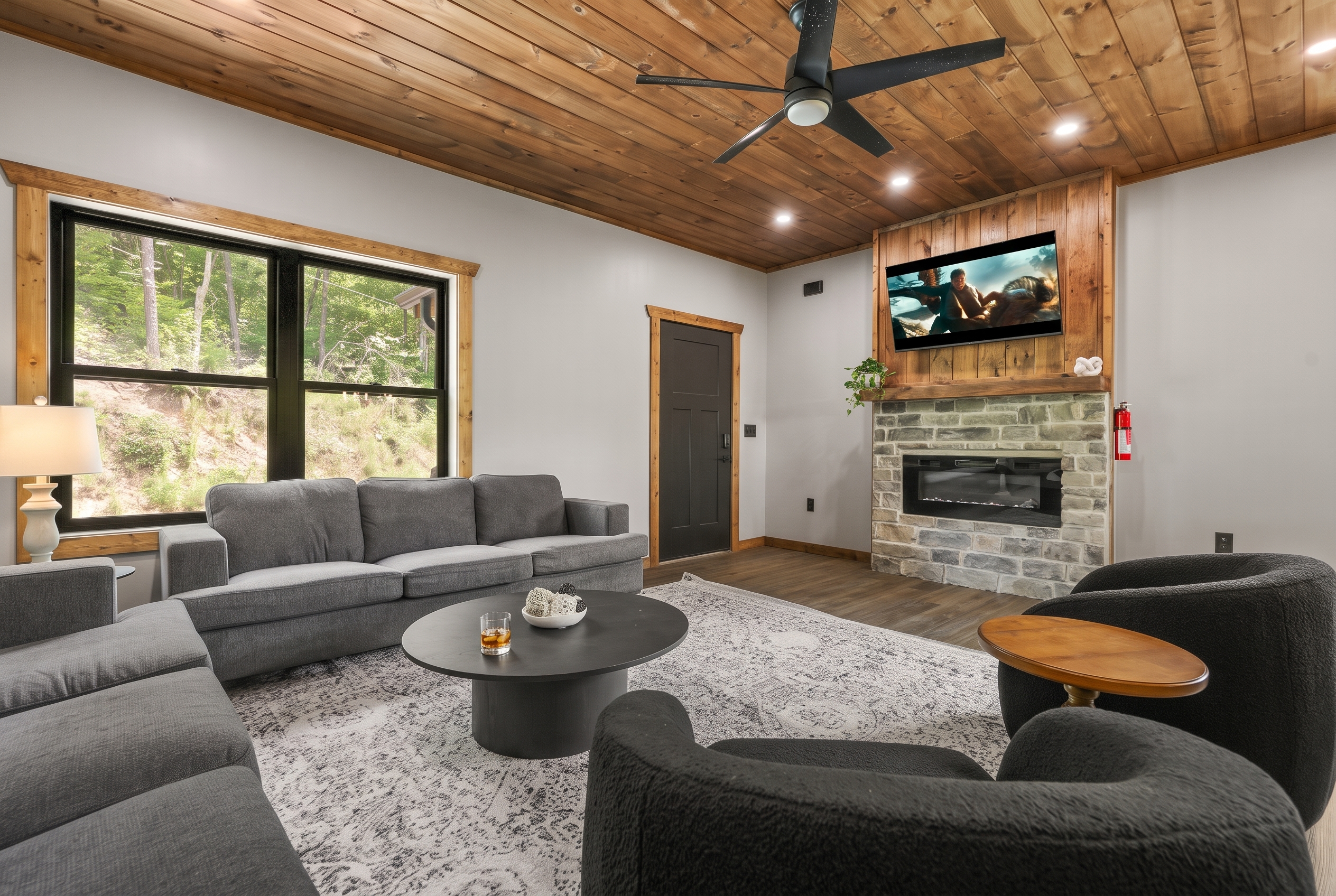 Cozy cabin-style living room with stone fireplace and forest views