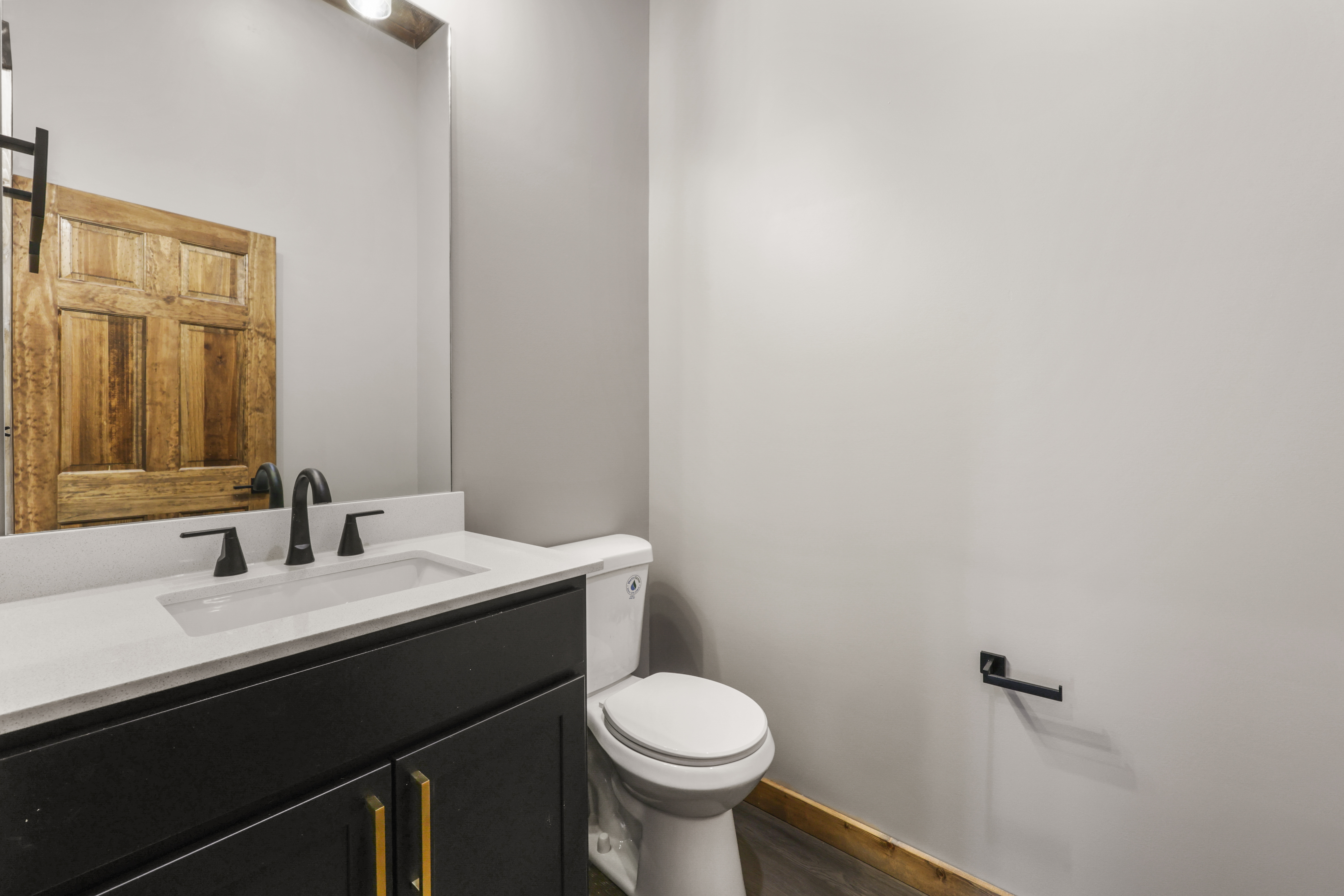 Stylish half bath with modern black fixtures and warm rustic touches