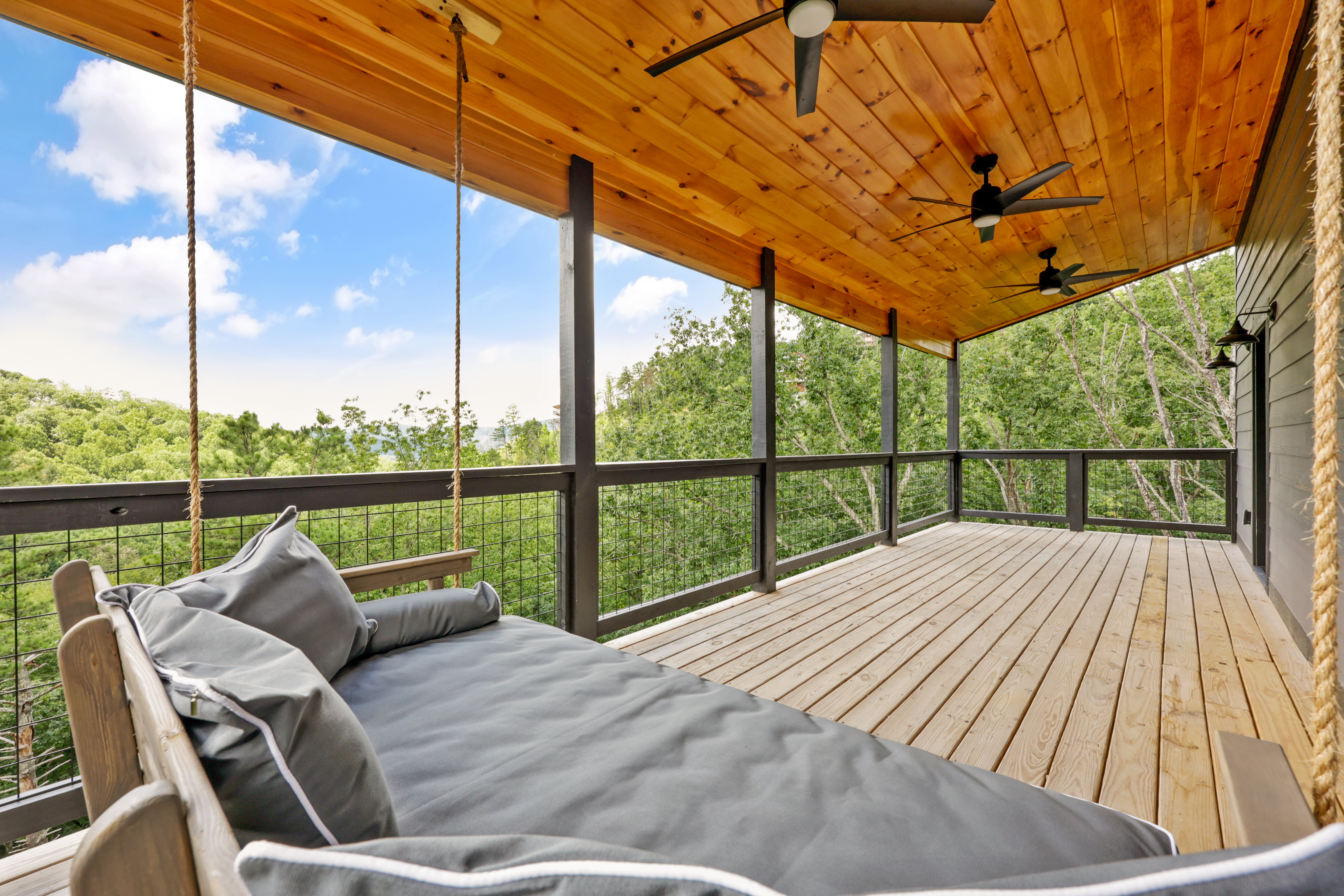Screened-in deck with hanging daybed and peaceful treetop views