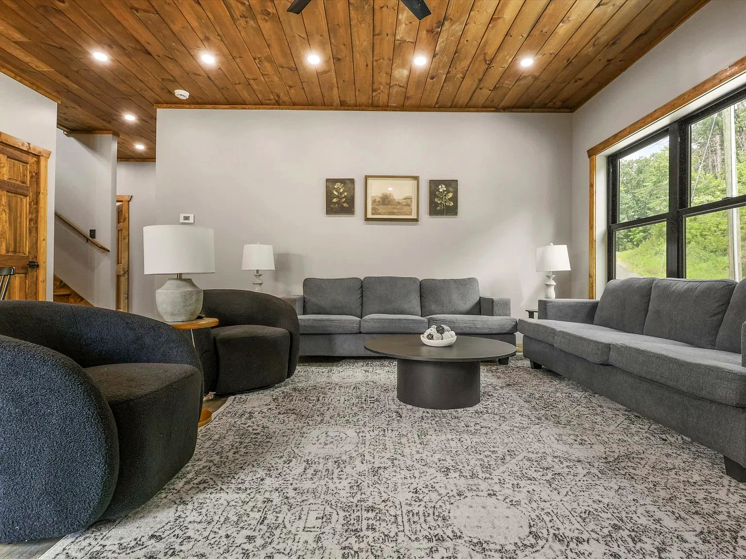 Bright, spacious living room with cozy seating and scenic forest views