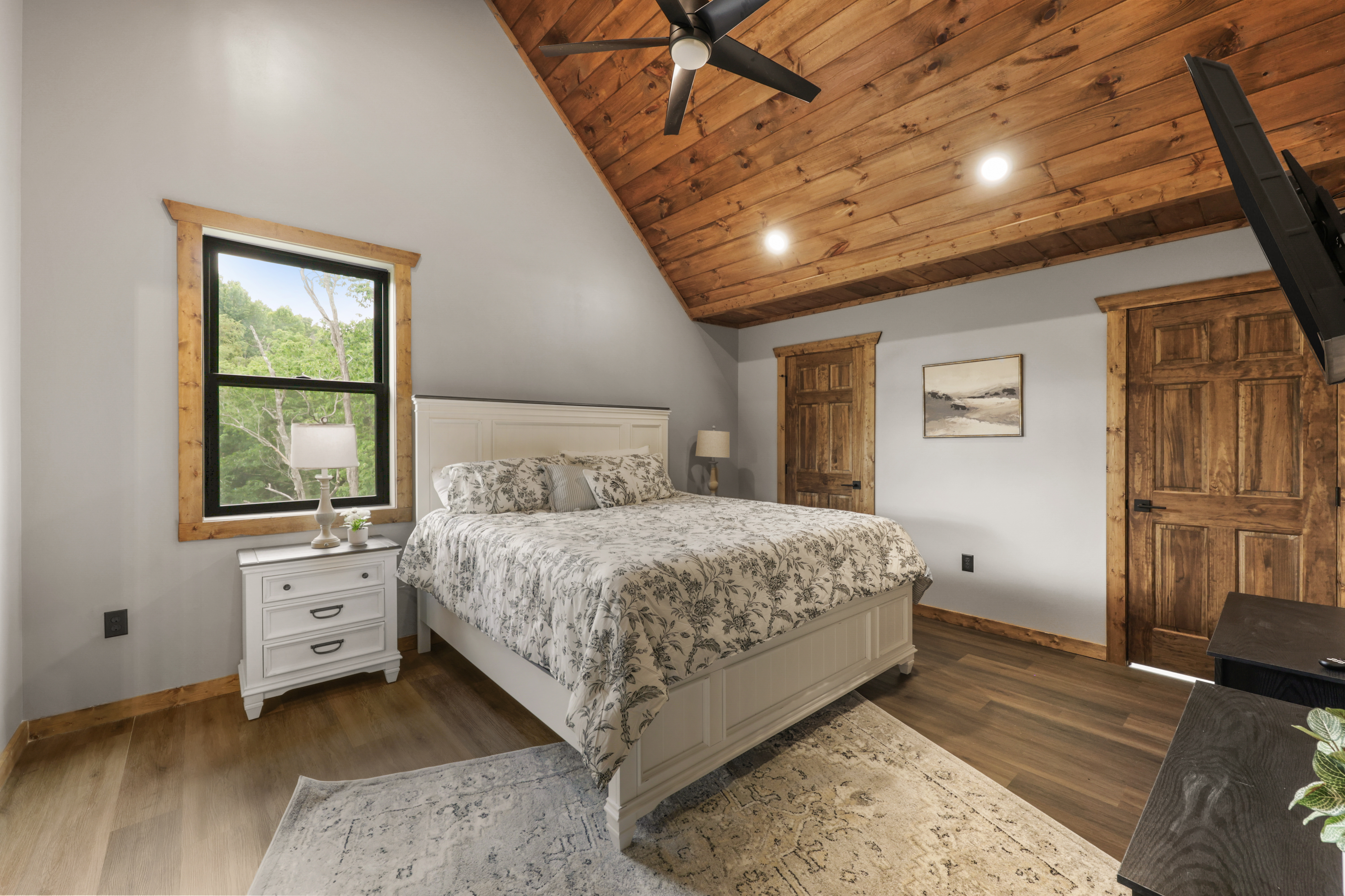 Warm rustic bedroom with vaulted wood ceilings and peaceful nature views
