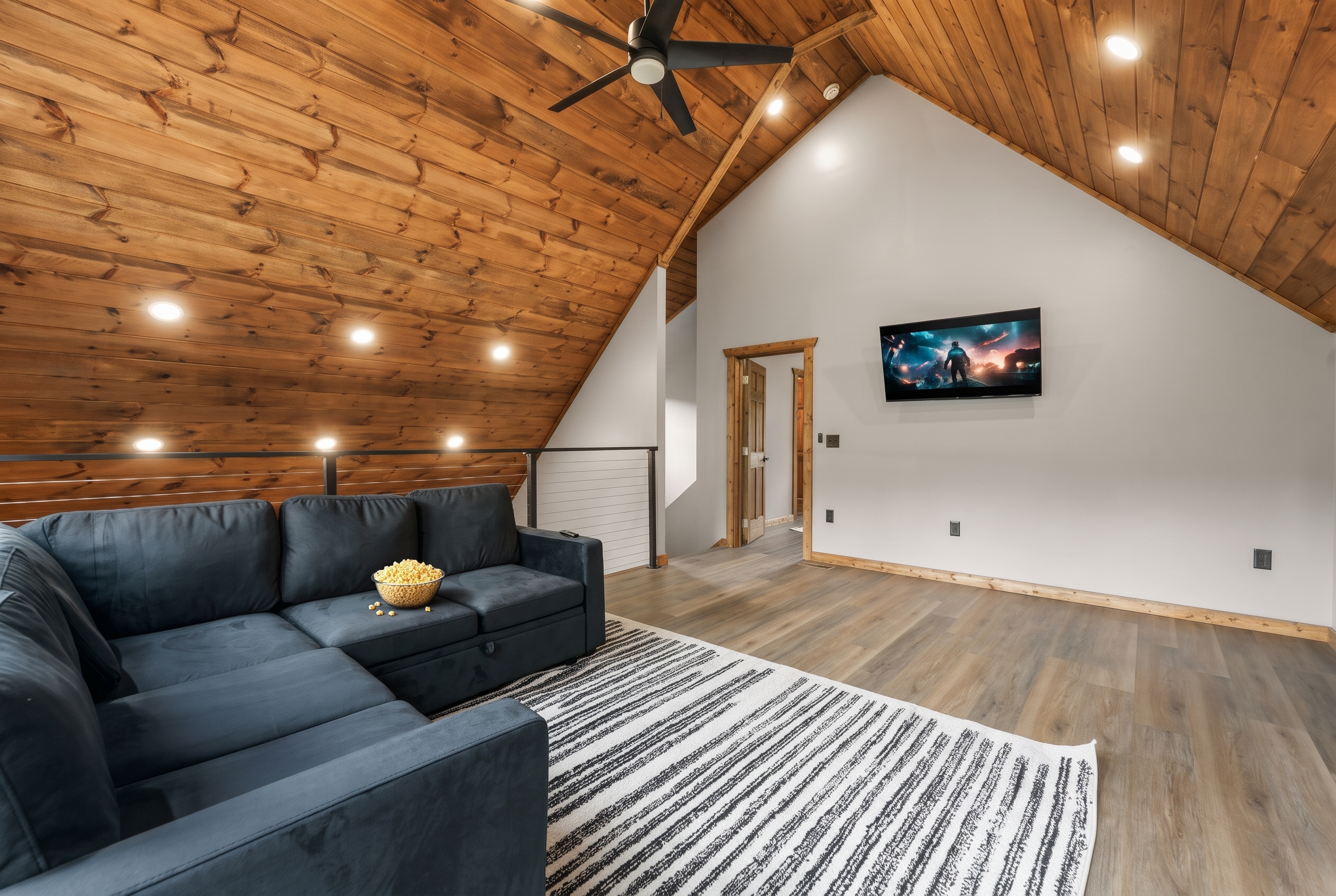 Cozy loft lounge with vaulted wood ceilings, large sectional, and TV