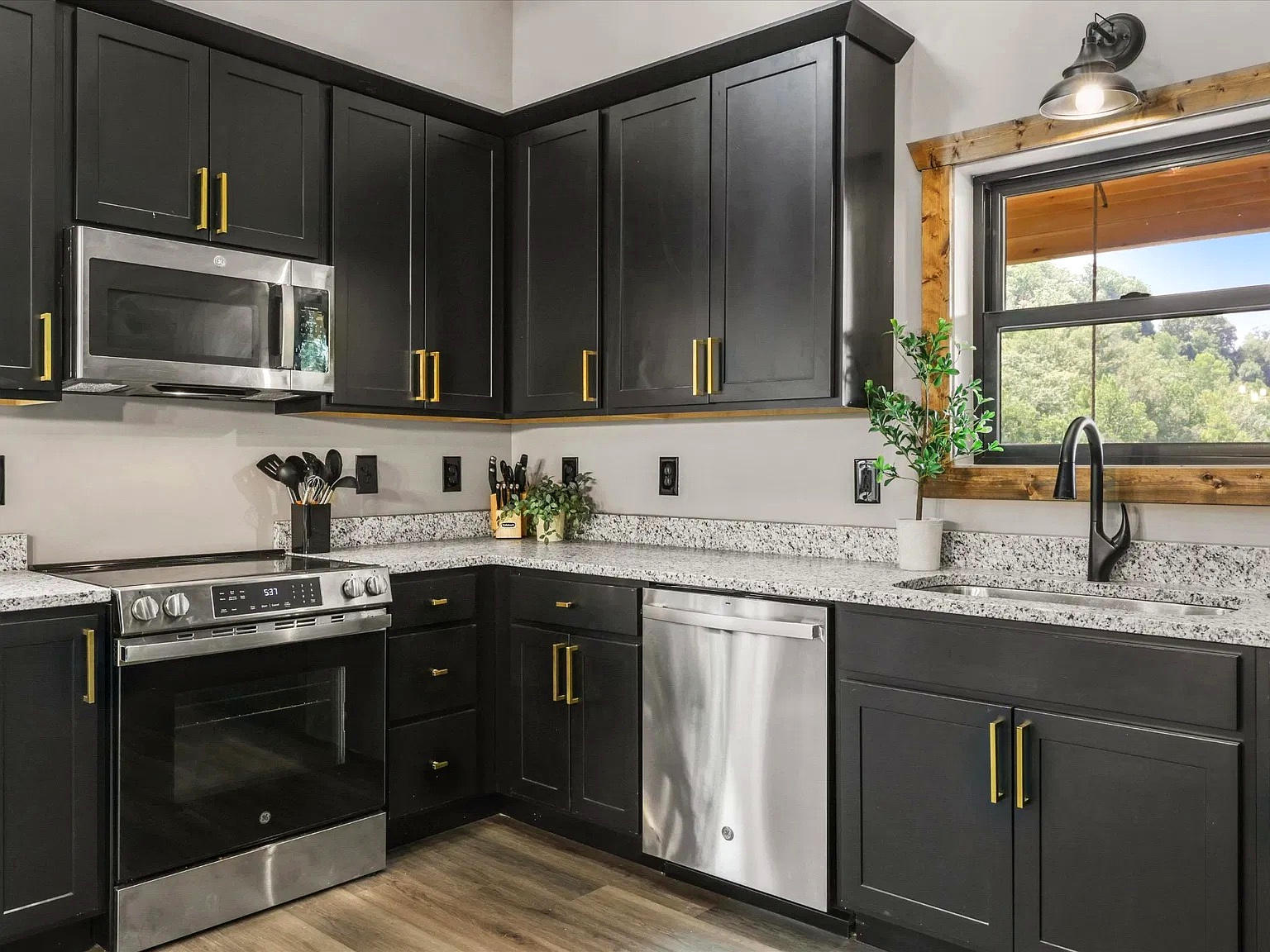 Modern kitchen with black cabinetry, granite counters, and scenic window view