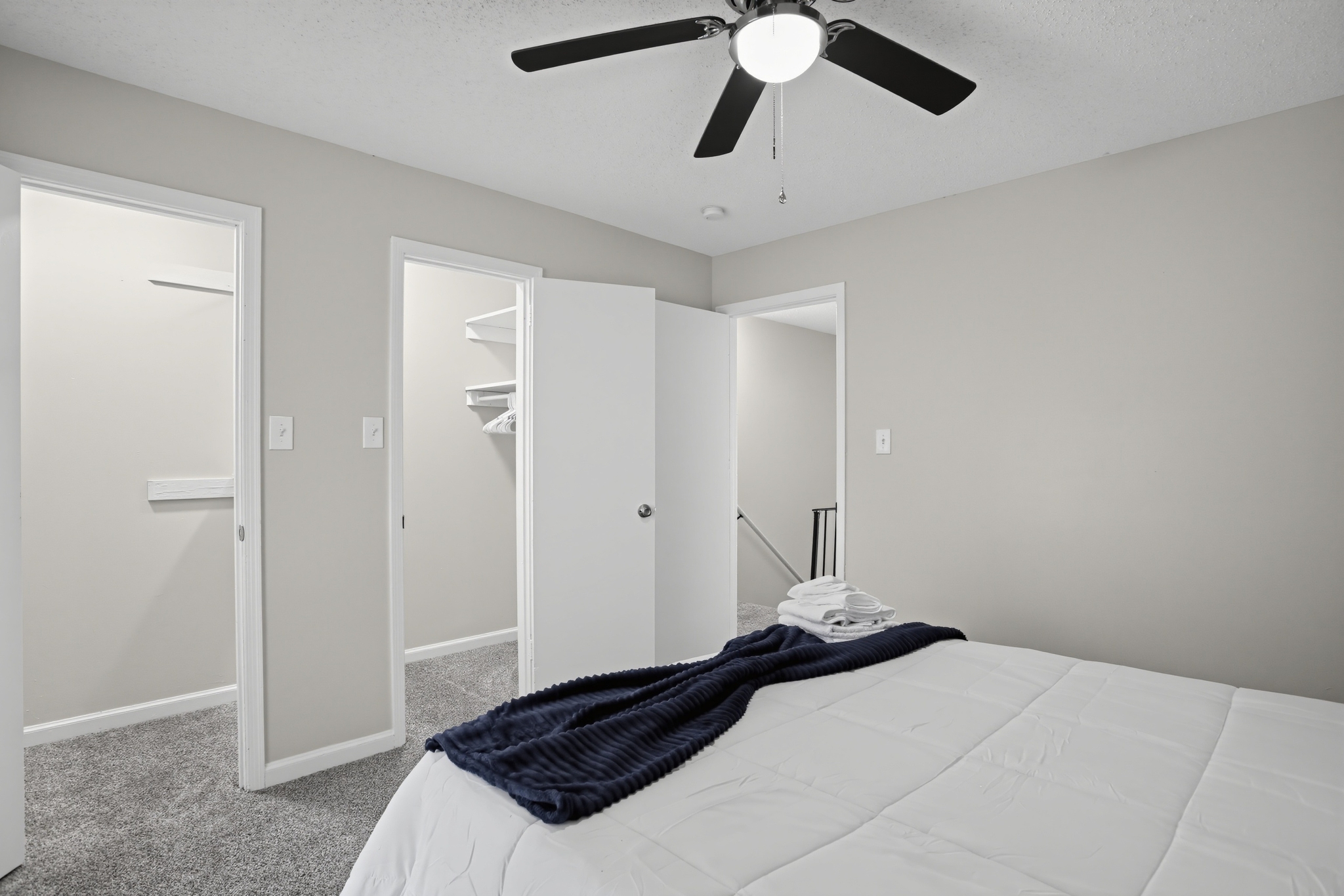 Bright, cozy bedroom with ceiling fan, soft carpet, and ample closet space