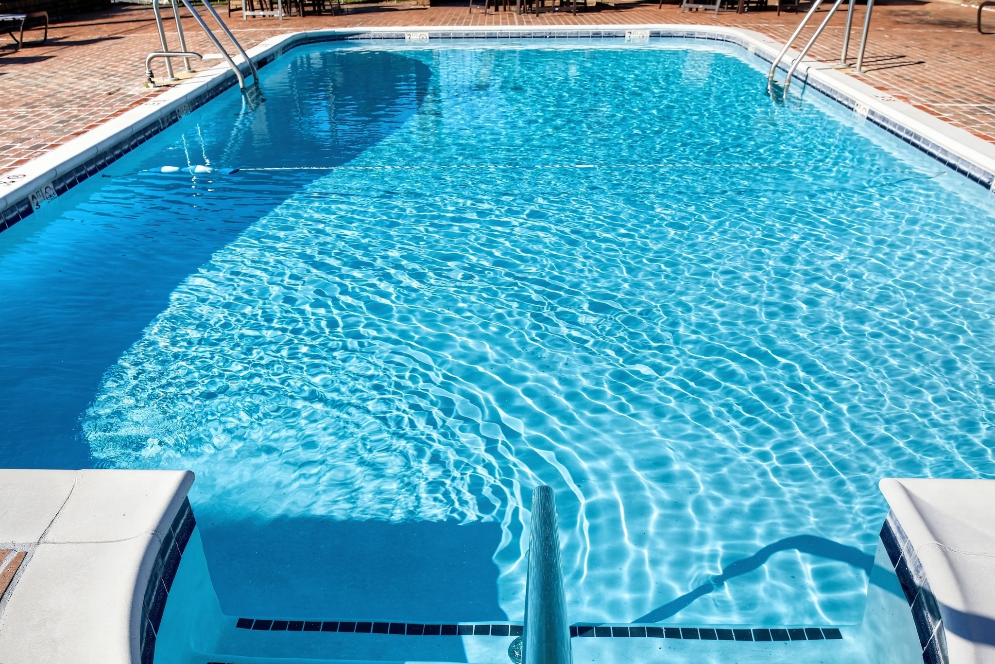 Sparkling outdoor pool with sunny brick deck and easy entry steps