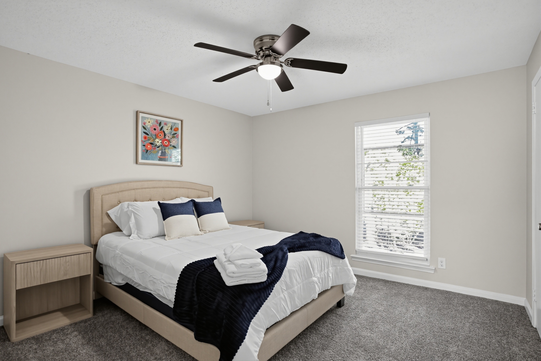 Bright, cozy bedroom with plush carpet, ceiling fan, and natural light