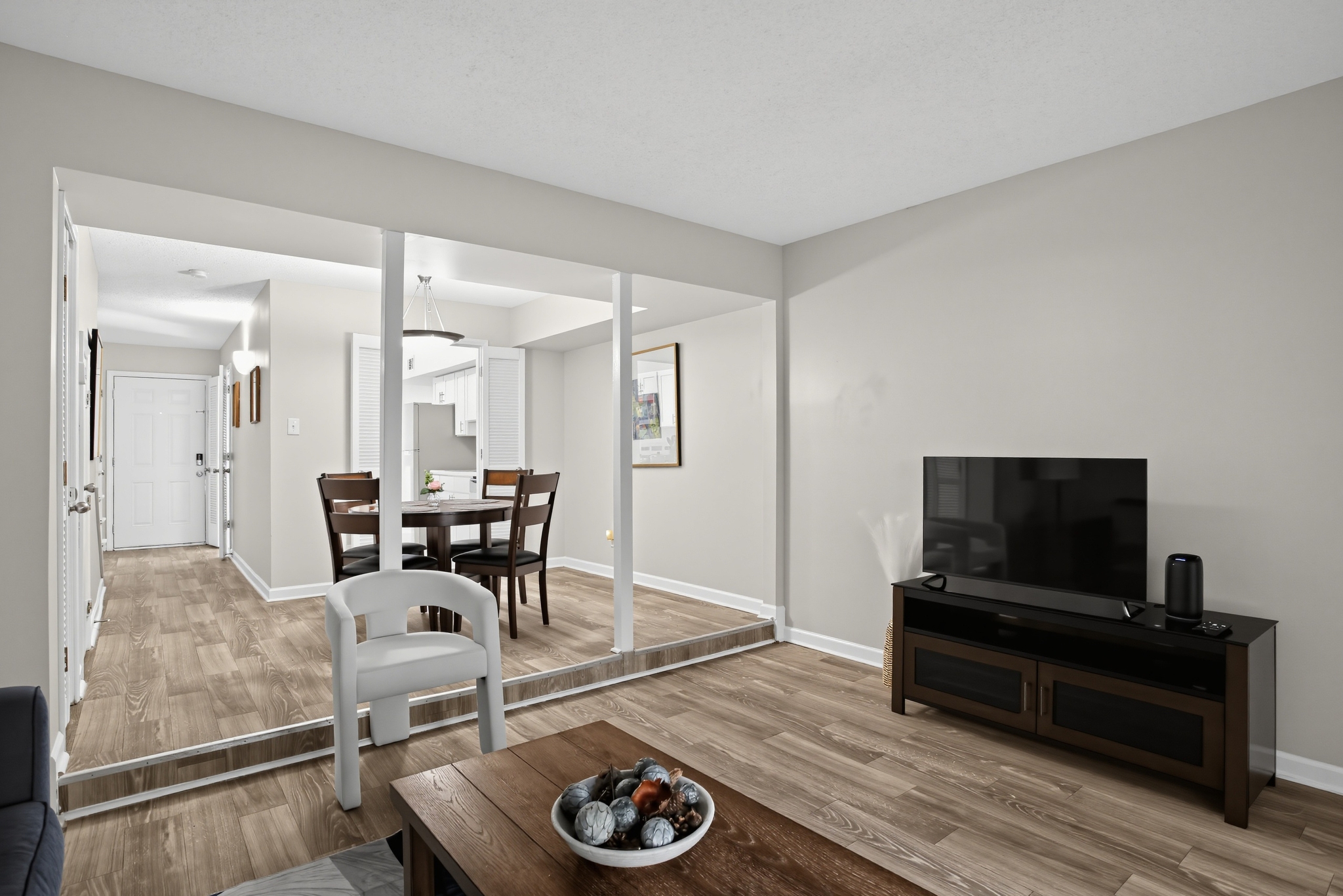 Bright open living room with TV, dining area, and modern wood-style floors