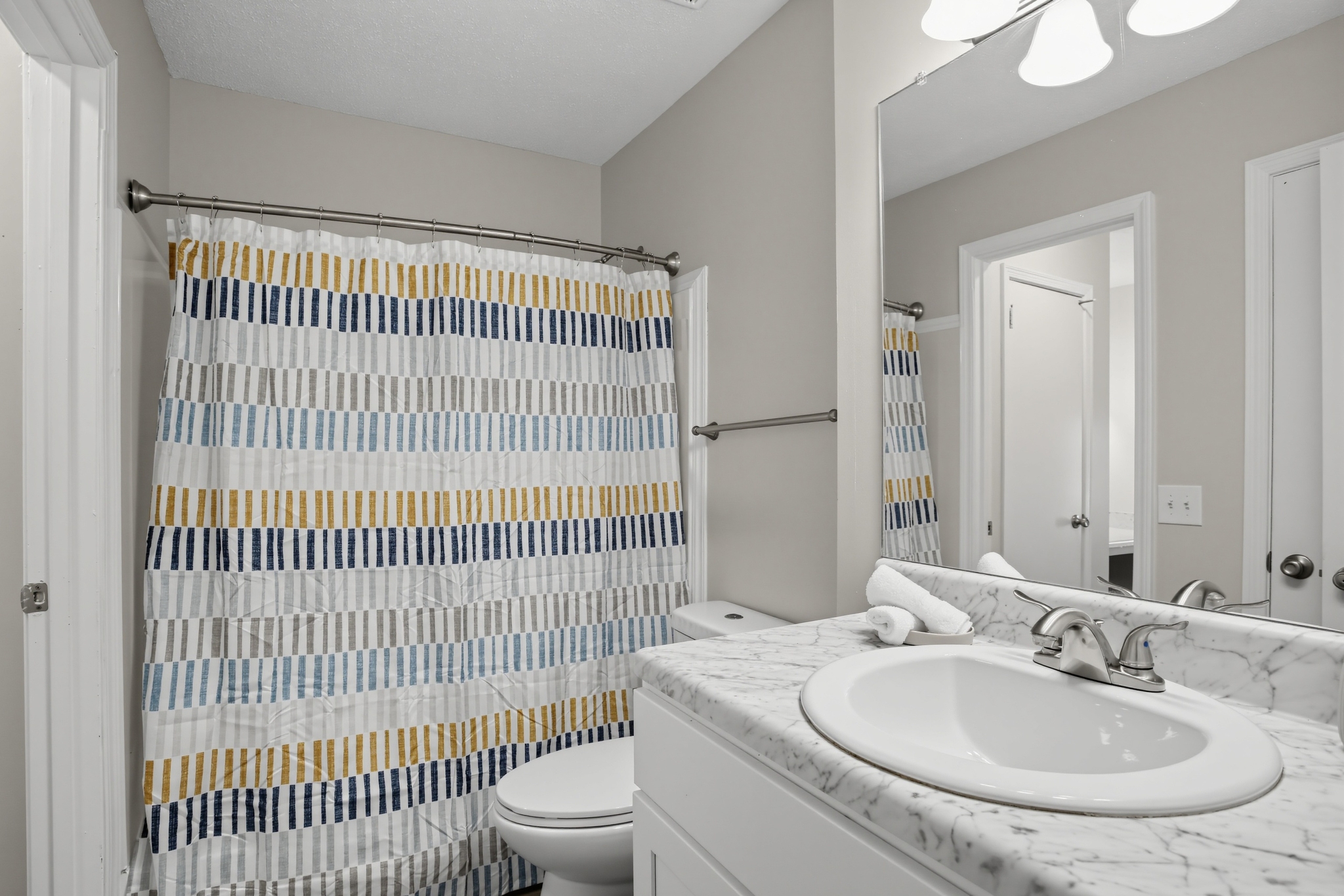 Bright bathroom with marble-look vanity and full shower-tub combo