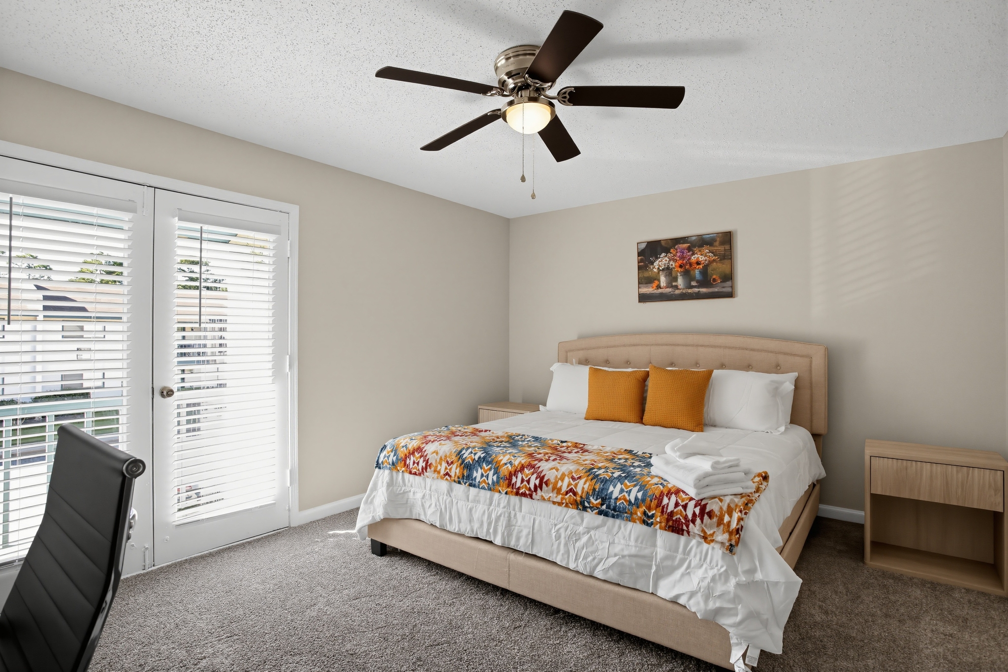 Bright, cozy bedroom with French doors, ceiling fan, and stylish accents