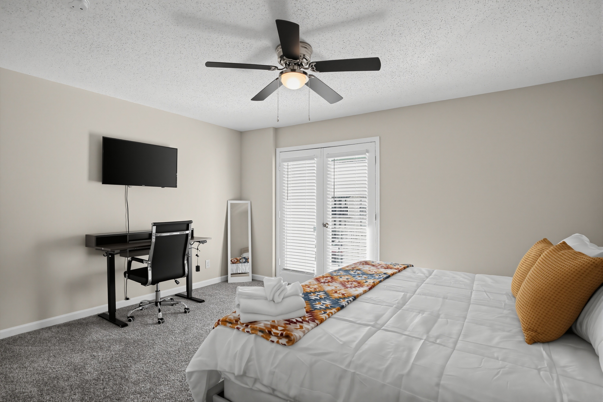Bright bedroom with workspace, TV, and French doors for added light