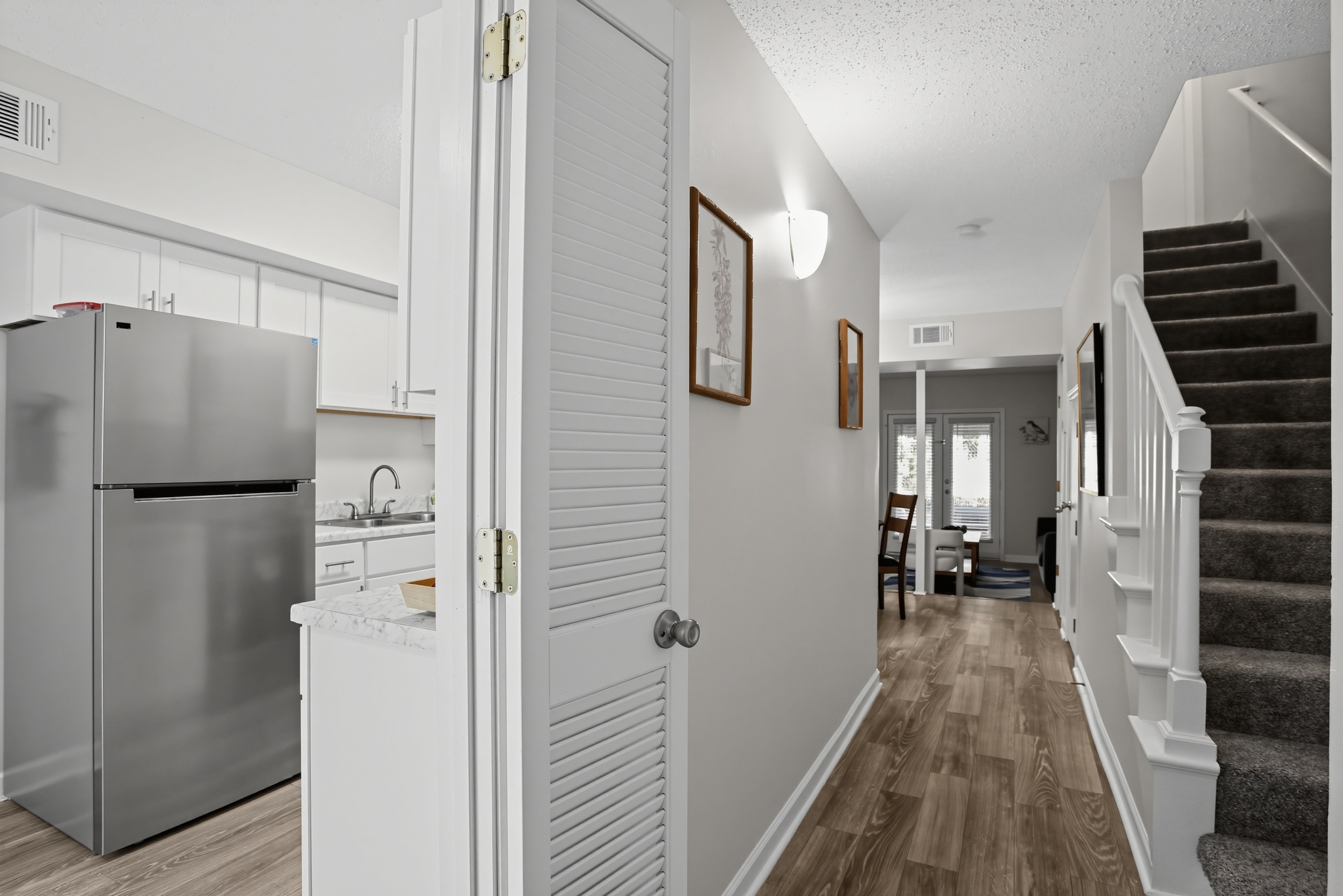 Bright entry hall with updated kitchen, wood-look floors, and staircase