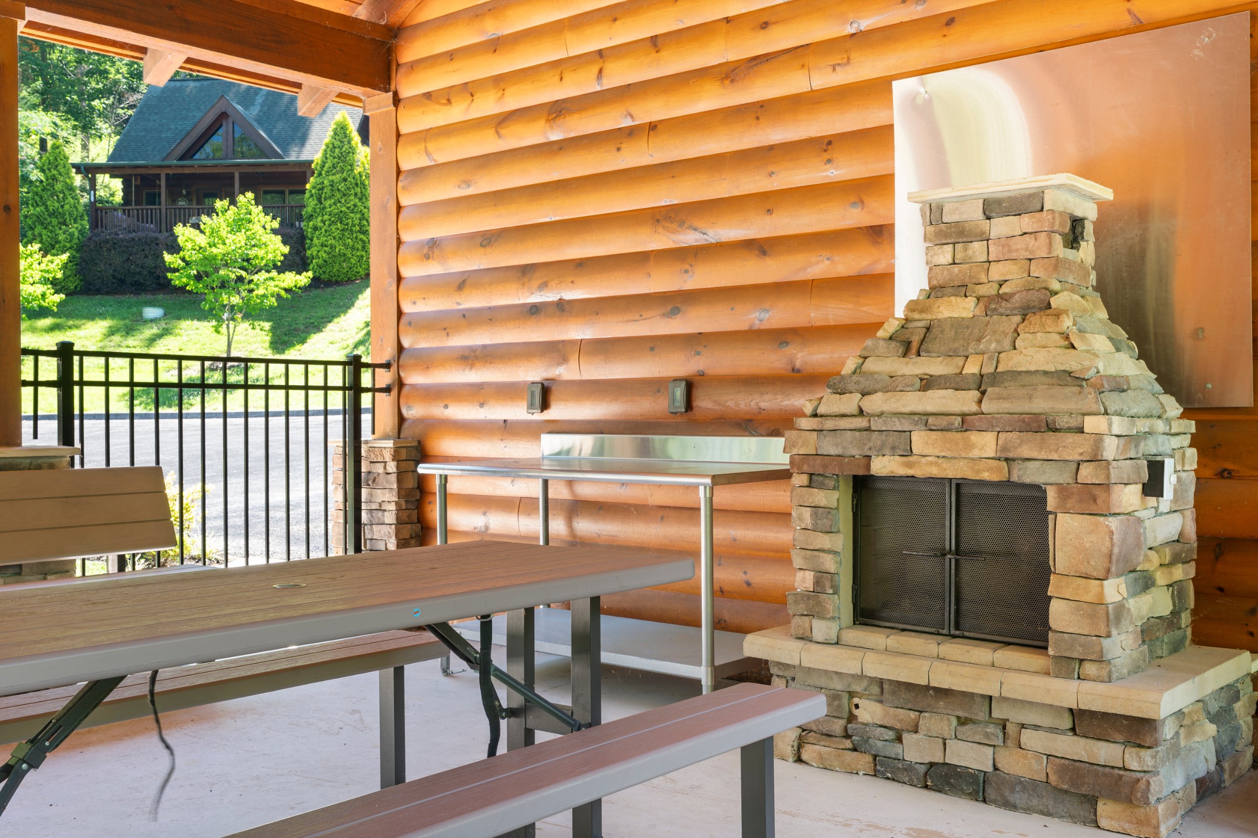 Shared community pavilion with a stone fireplace and picnic tables, used by all cabins in Smoky Mountain Ridge.