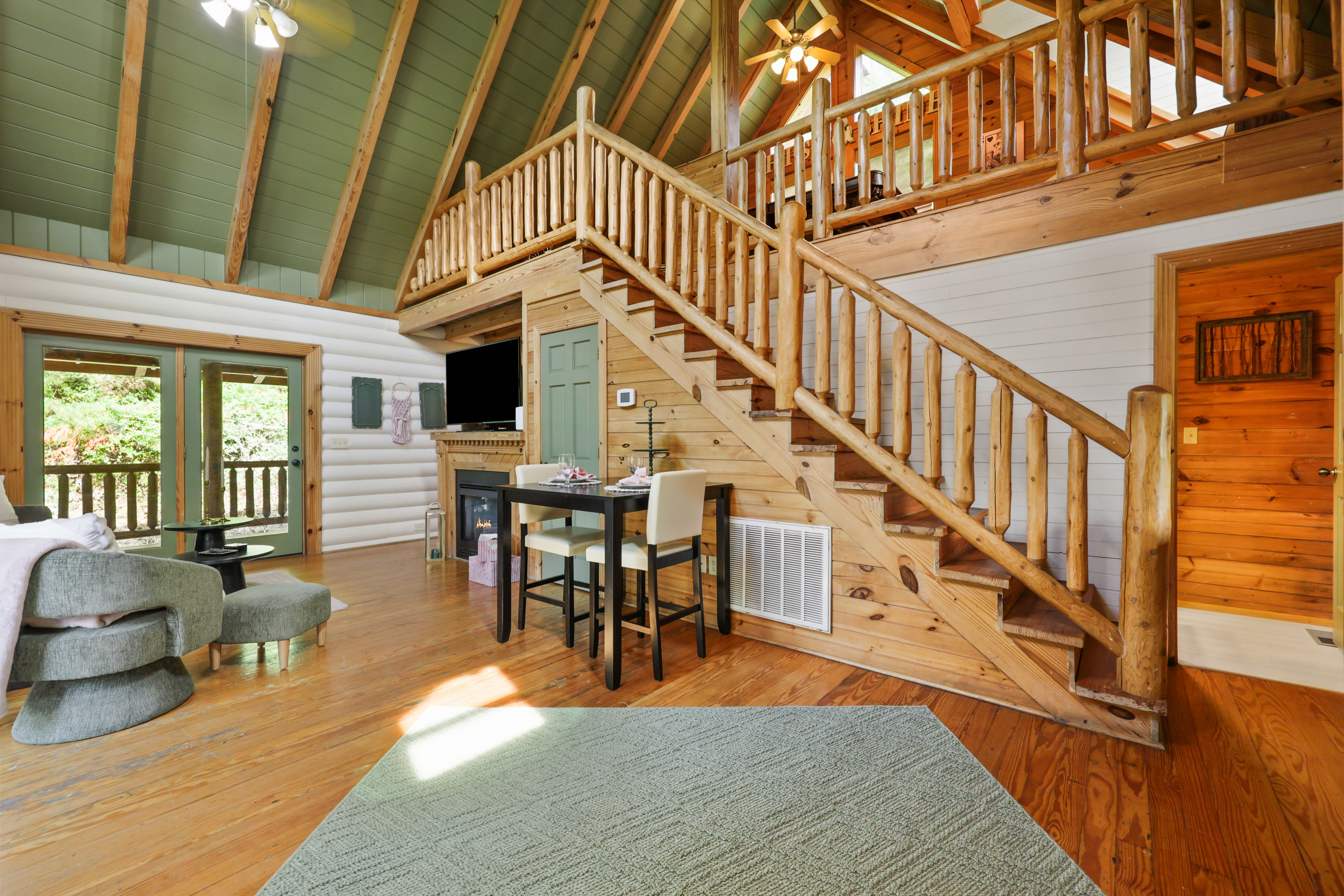 Rustic cabin great room with loft, fireplace, and sunny deck access