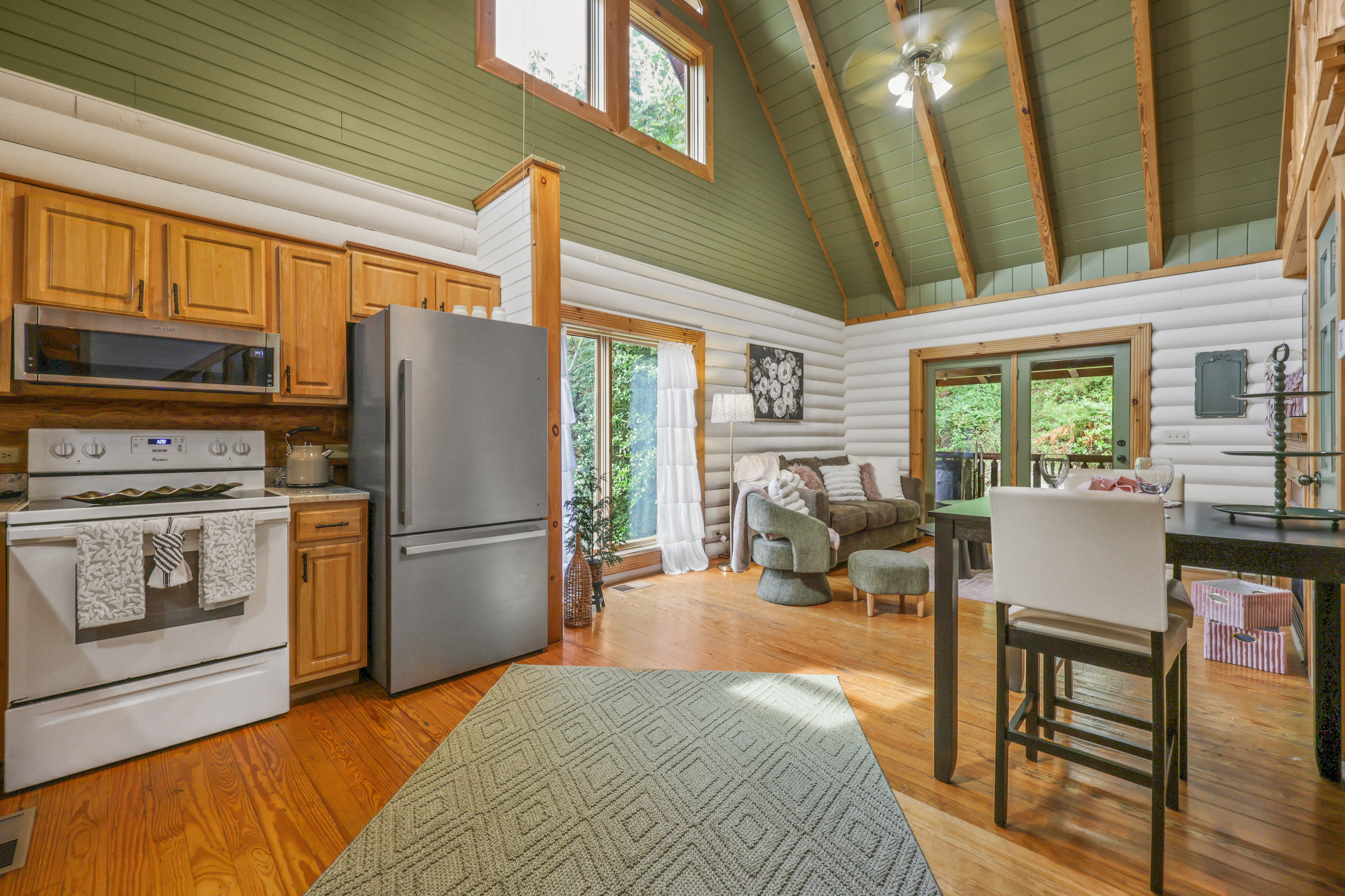 Bright cabin great room with vaulted ceilings, full kitchen, and woodland views
