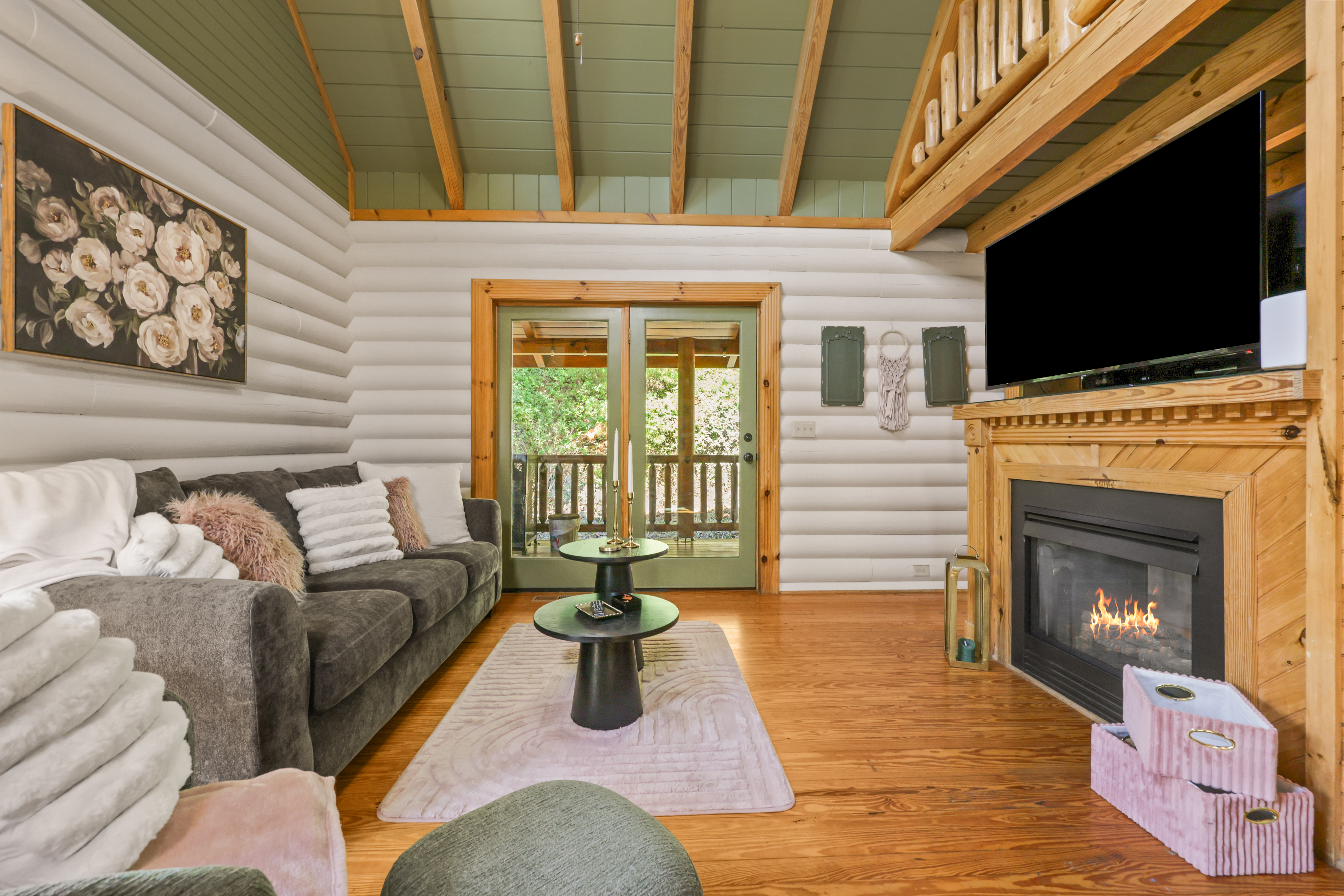 Cozy cabin living room with fireplace, TV, and deck access