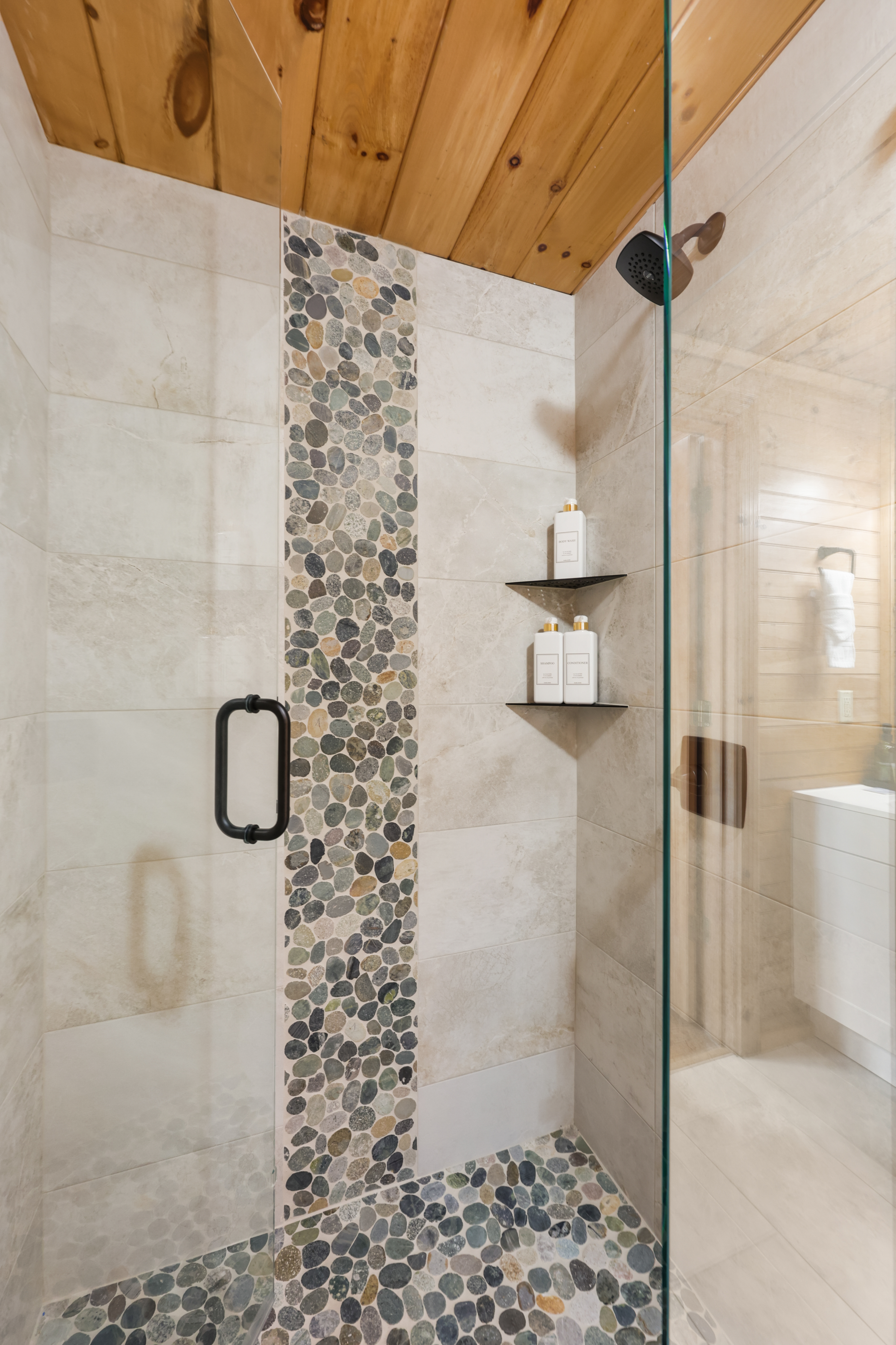 Spa-style walk-in shower with pebble tile accents and sleek glass enclosure