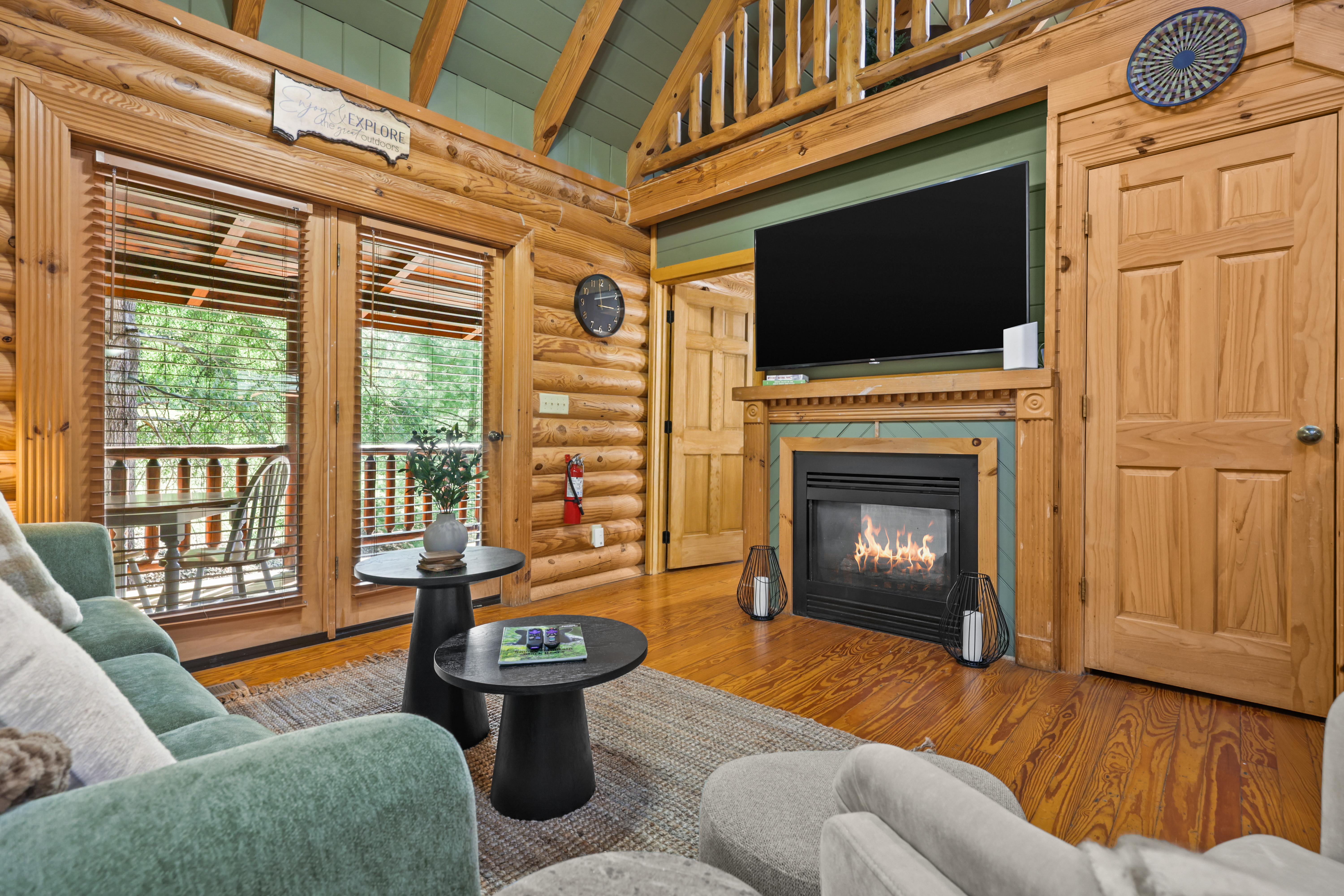 Cozy log cabin lounge with fireplace, TV, and deck access