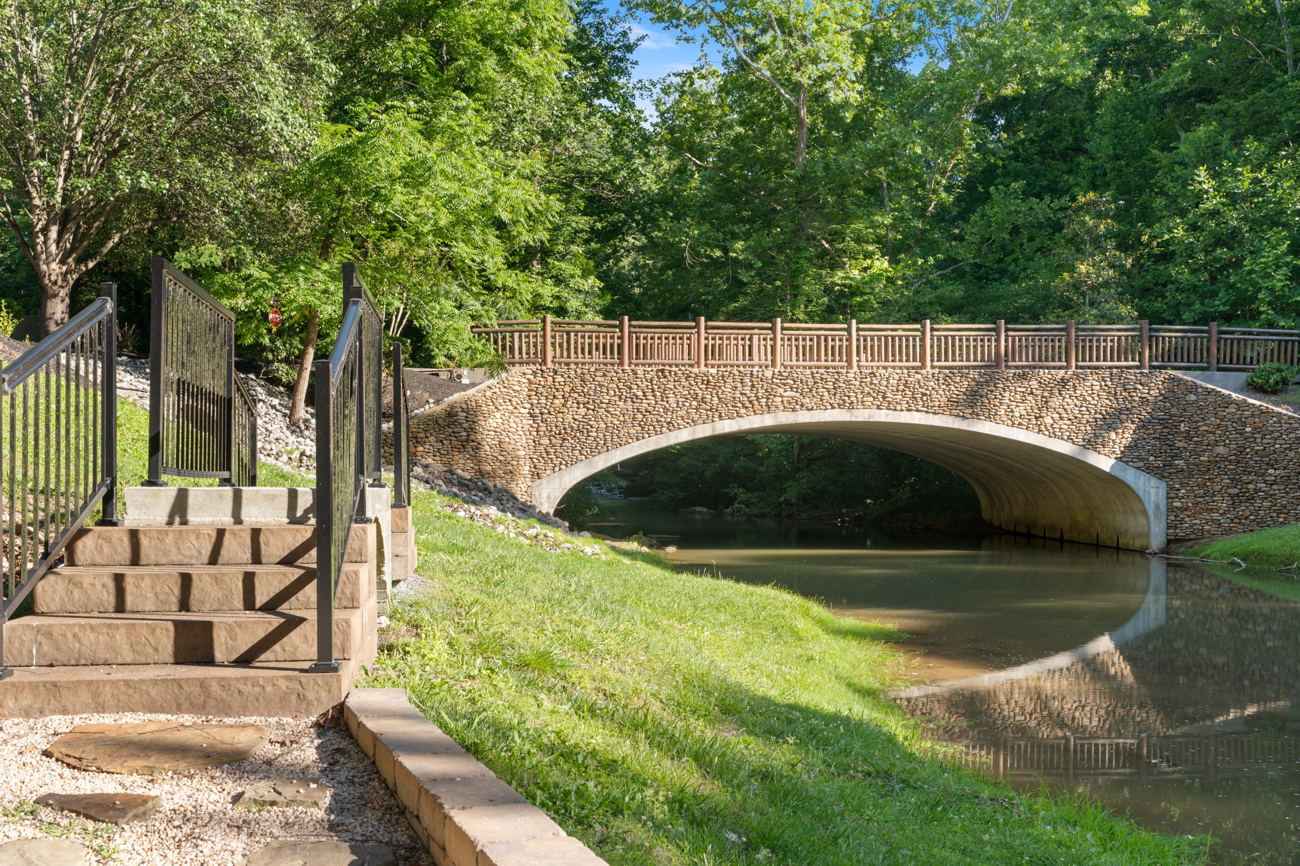 Stone bridge over the community creek, a shared spot for a walk. Supervise children near the water.