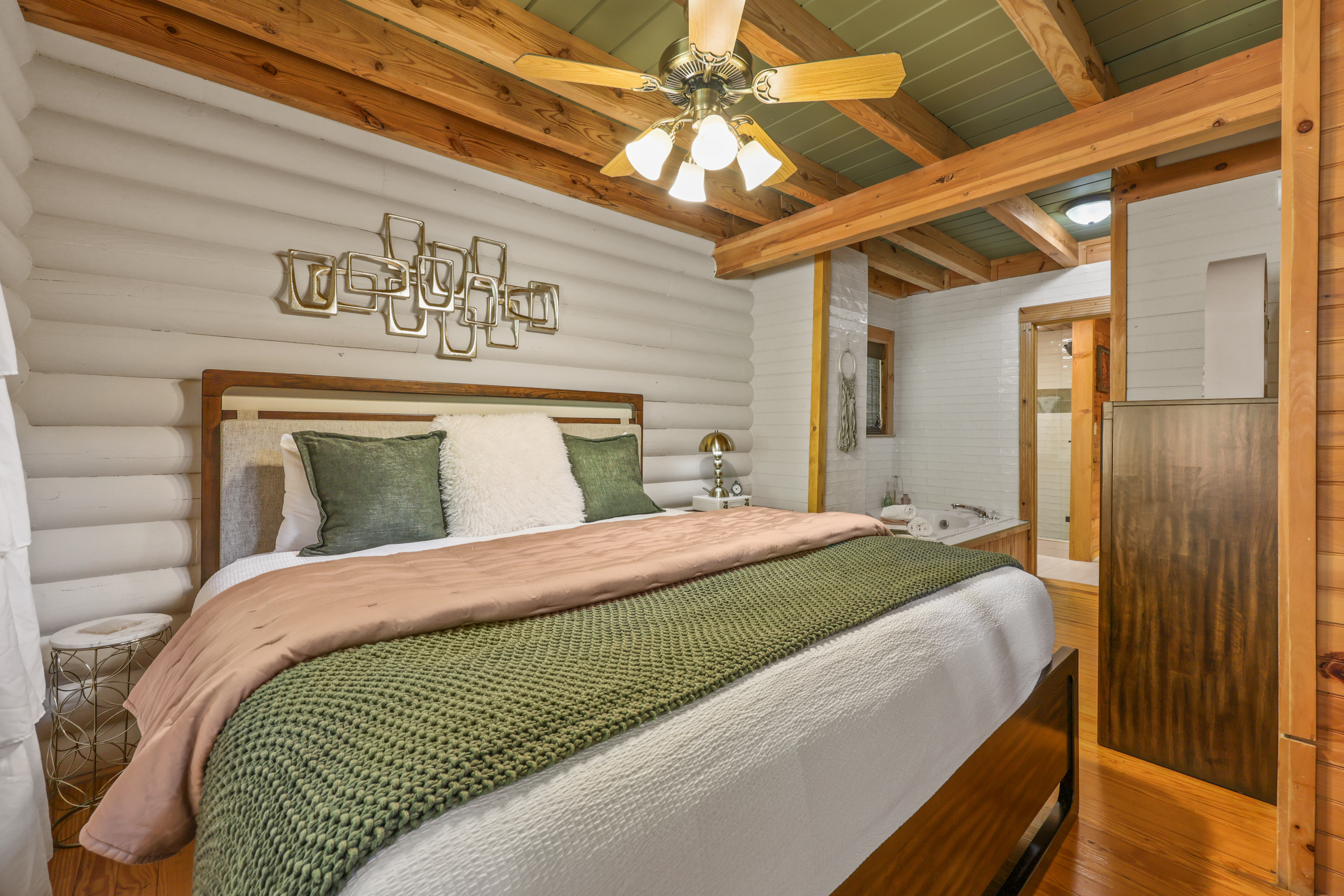 Cozy cabin-style bedroom with exposed beams and a relaxing soaking tub