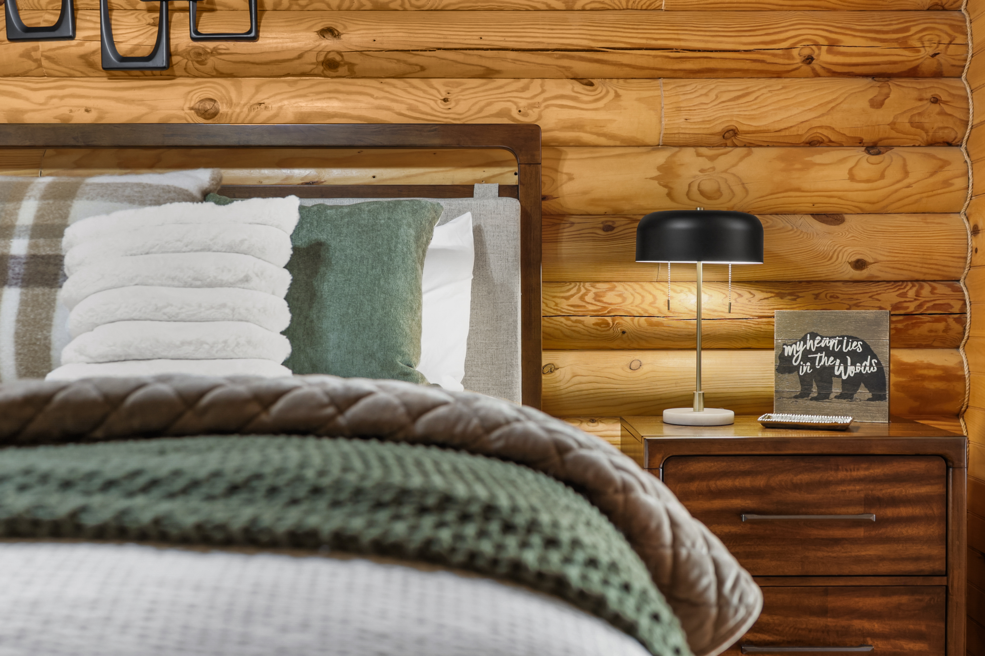 Cozy log cabin bedroom with layered bedding and warm rustic charm