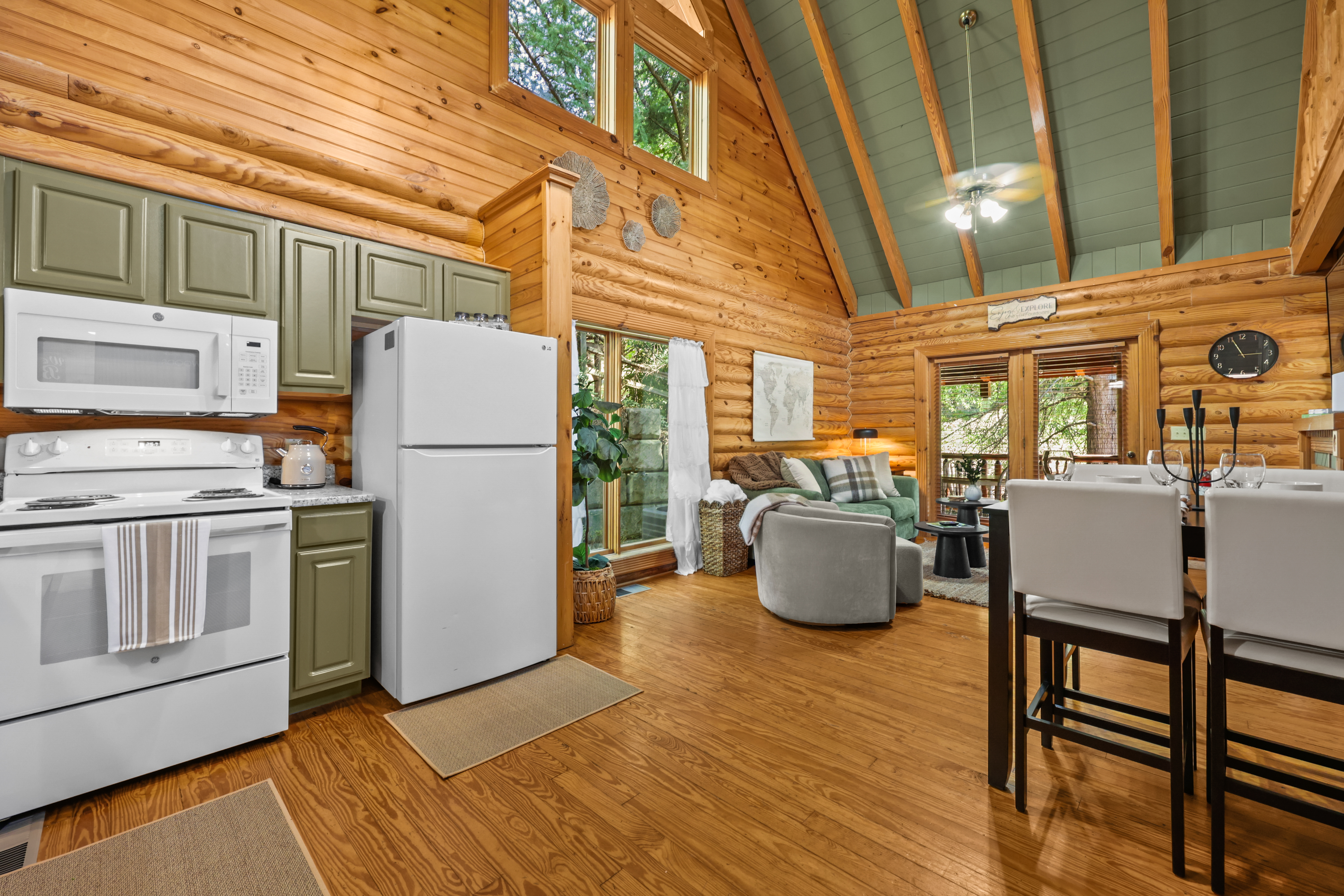 Open-concept log cabin with vaulted ceilings, cozy lounge, and deck access