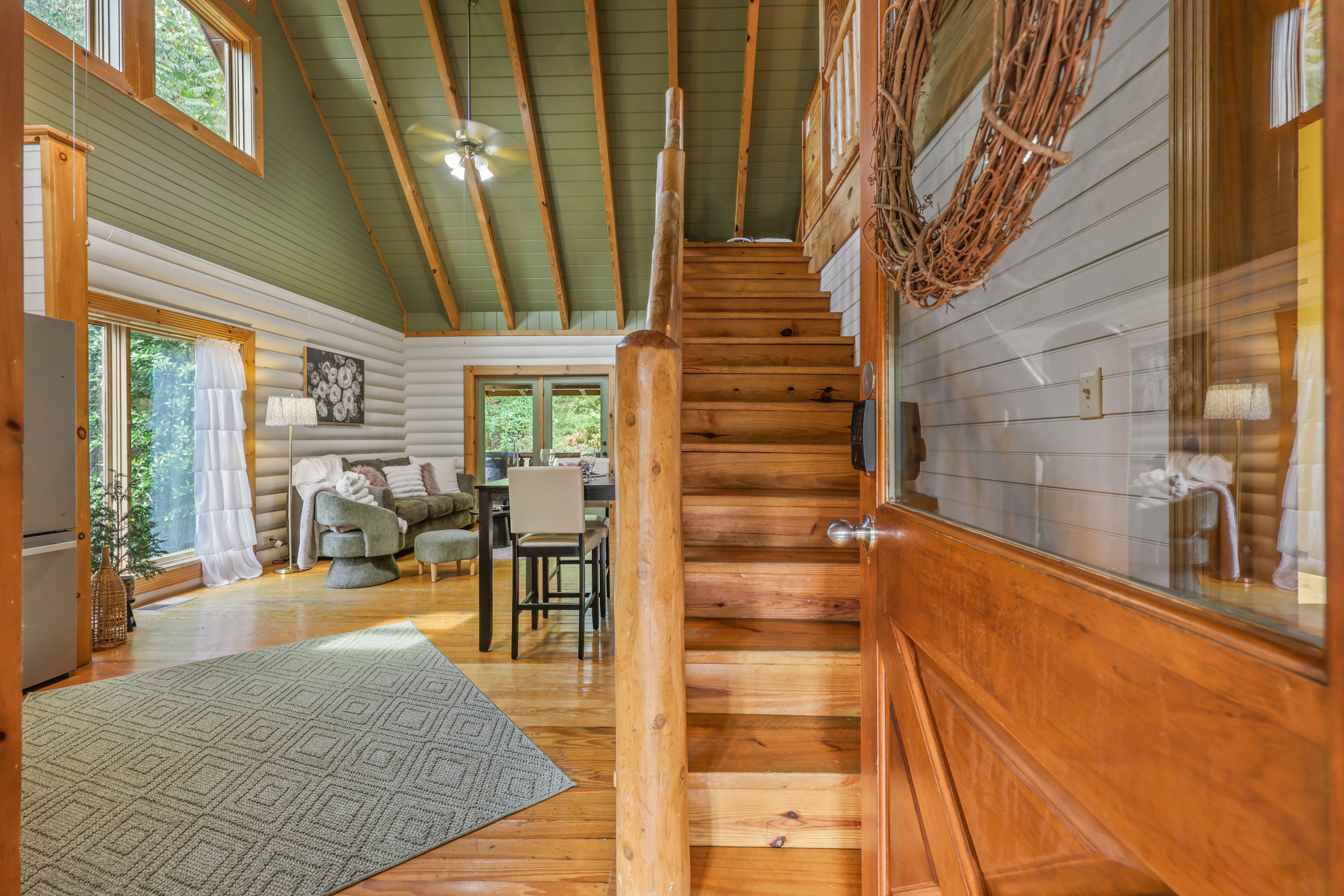 Bright cabin entry with soaring ceilings, rustic wood details, and open living space