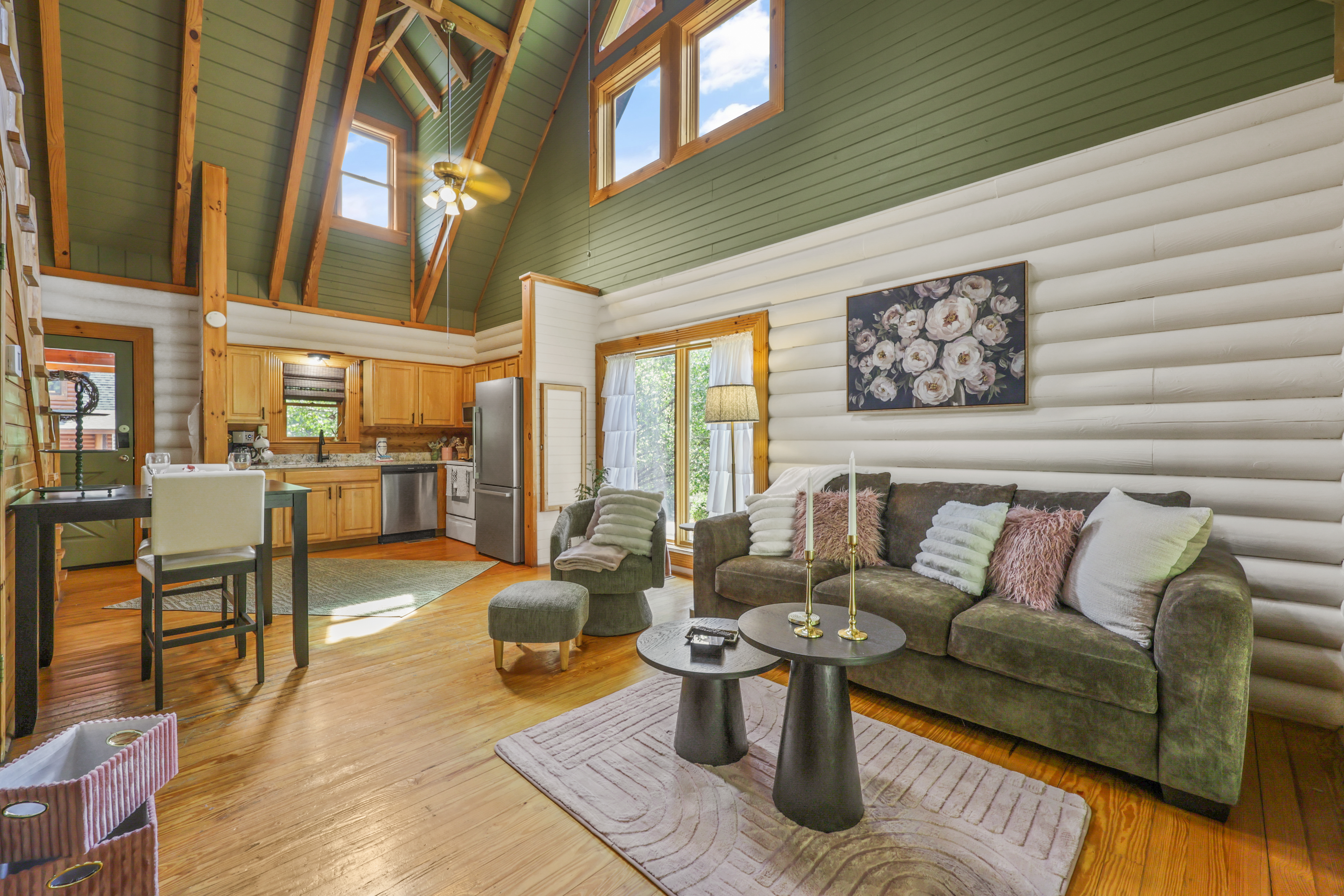 Vaulted cabin living with cozy seating, natural light, and full kitchen