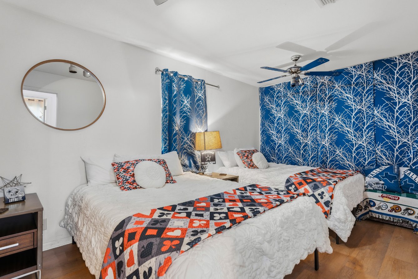 Bright double bedroom with bold blue accent wall and cozy stylish beds