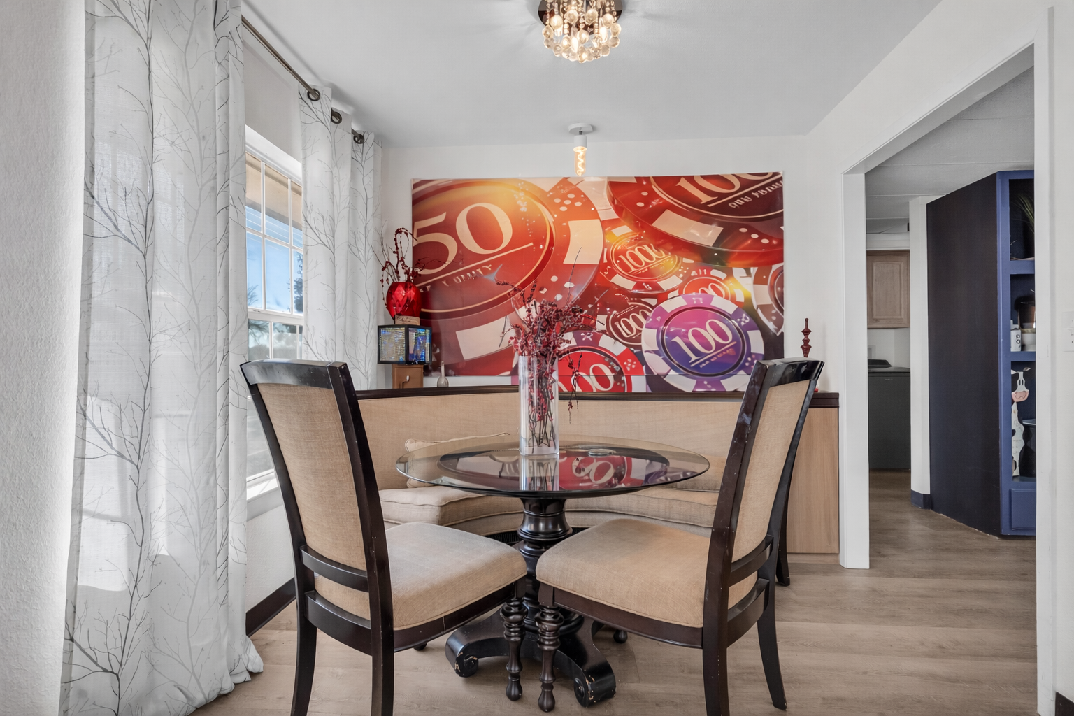 Bright modern dining nook with glass table, bold art, and natural light