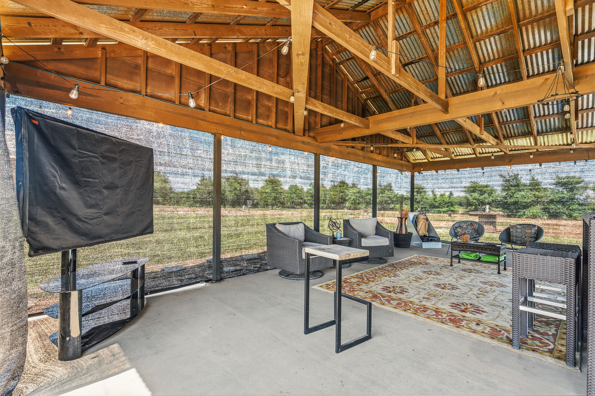 Screened-in outdoor lounge with TV, cozy seating, and scenic views