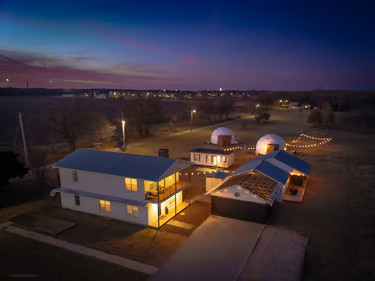 Twilight aerial view with glowing domes and a spacious countryside retreat