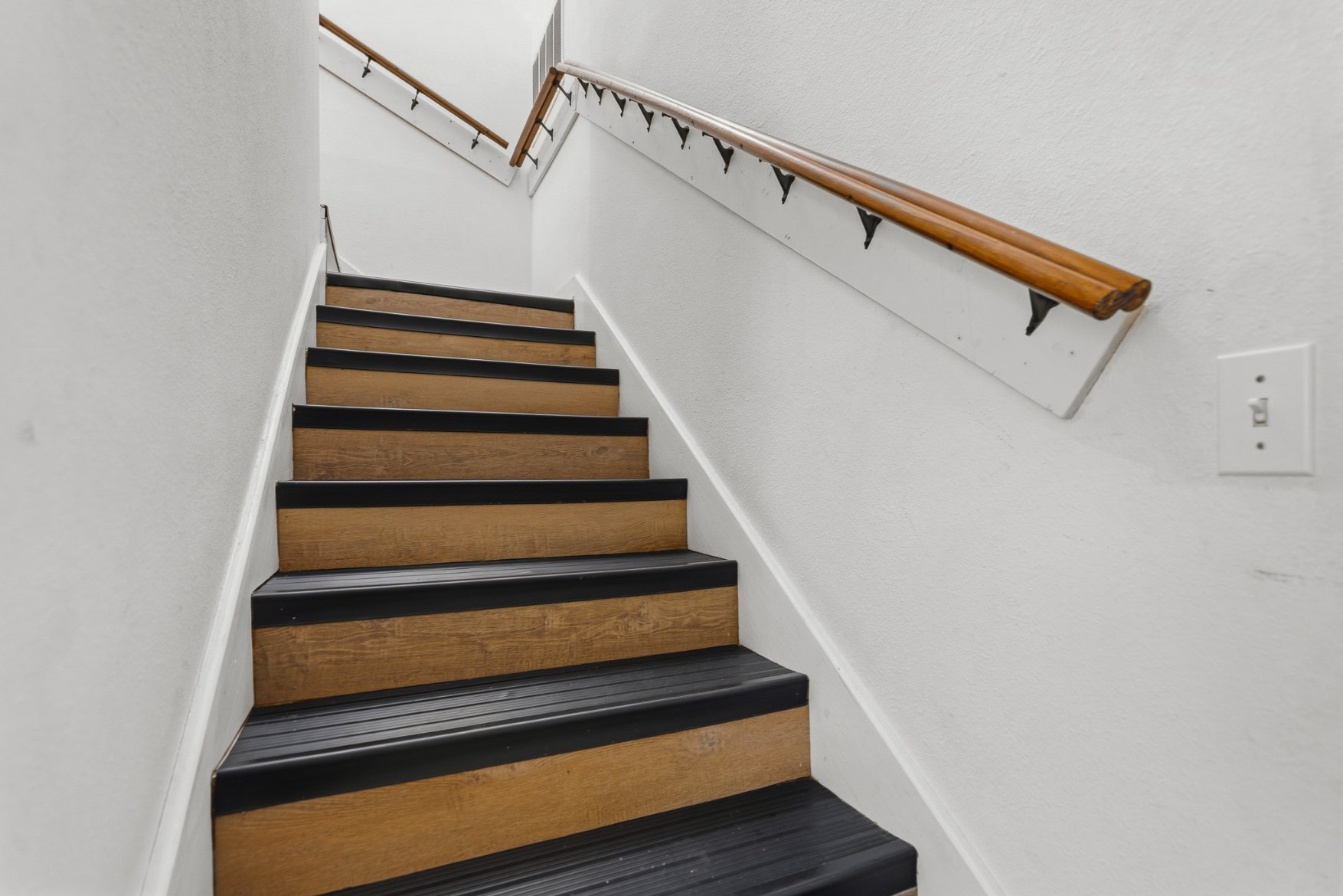 Clean, bright staircase with sturdy handrails and modern wood-look steps