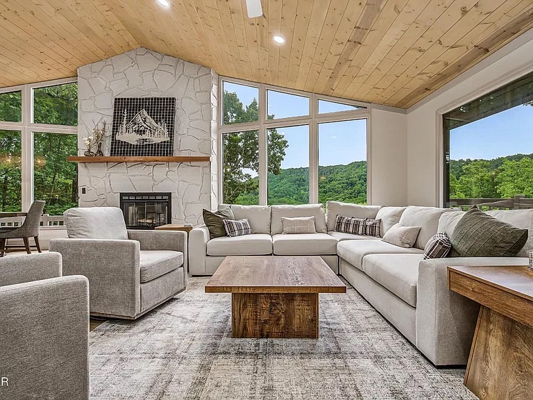 Bright mountain-view living room with stone fireplace and large sectional