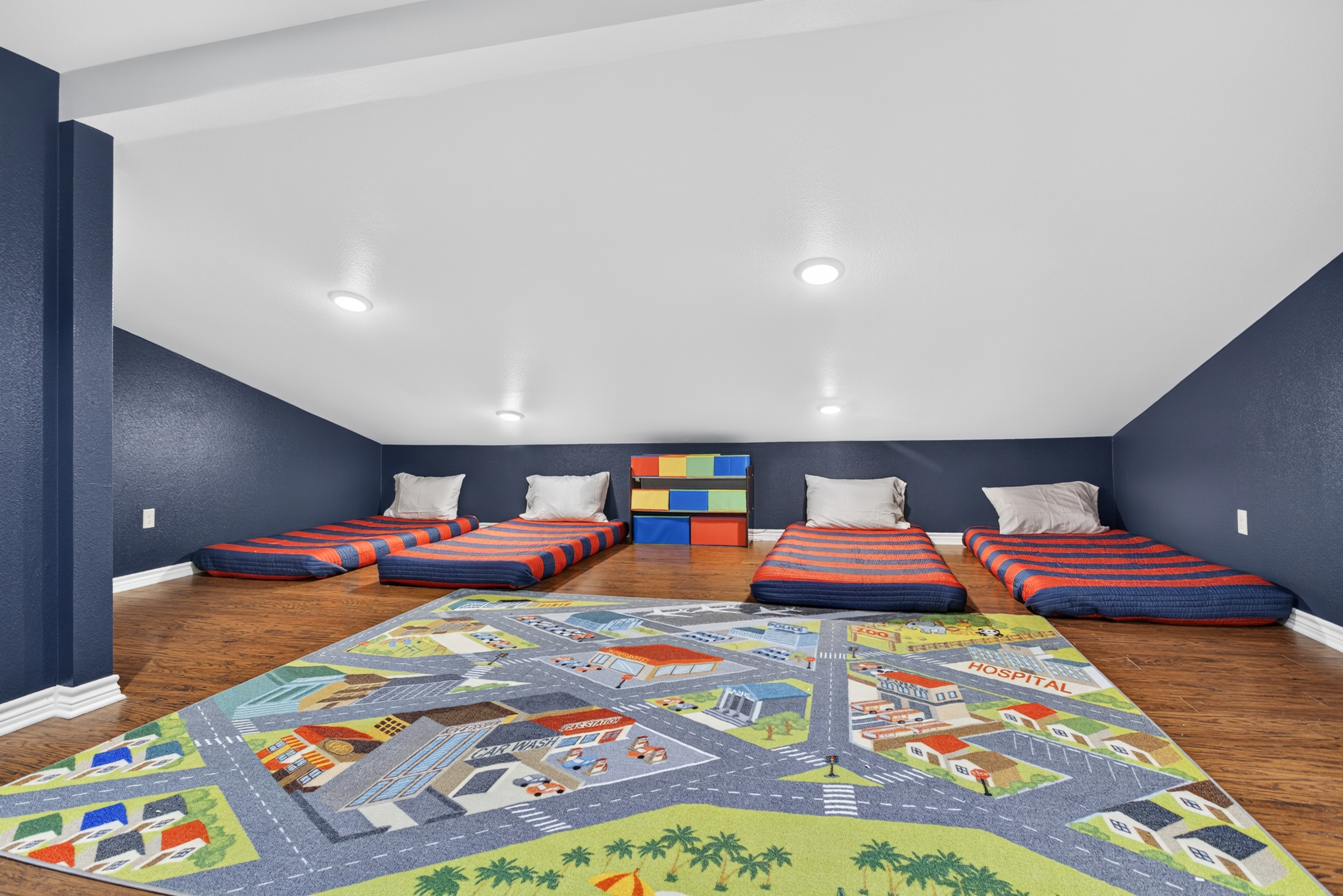 Fun loft sleepover space with 4 floor beds and a colorful play rug
