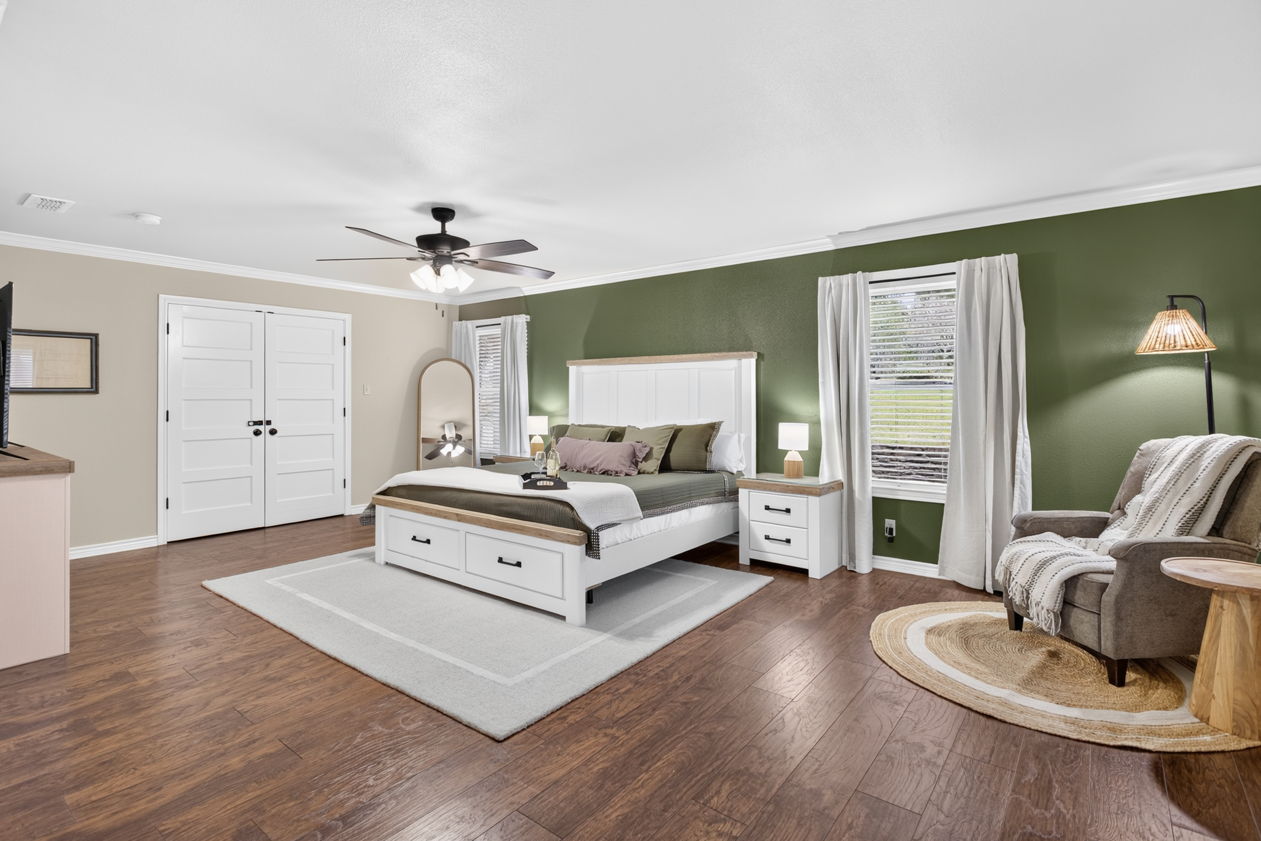 Spacious king bedroom with reading nook, accent wall, and warm wood floors