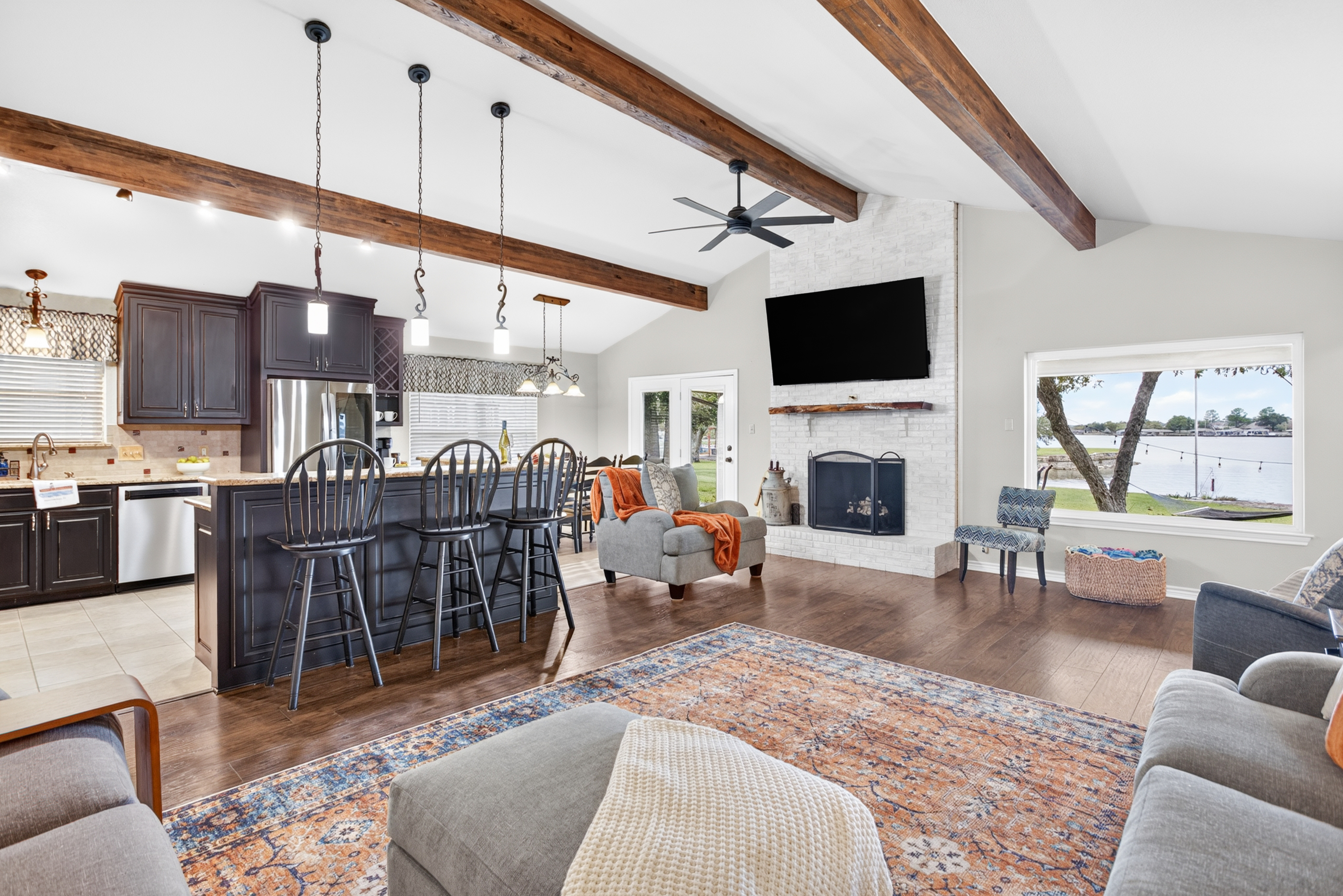 Open-concept great room with fireplace, large island, and lake views