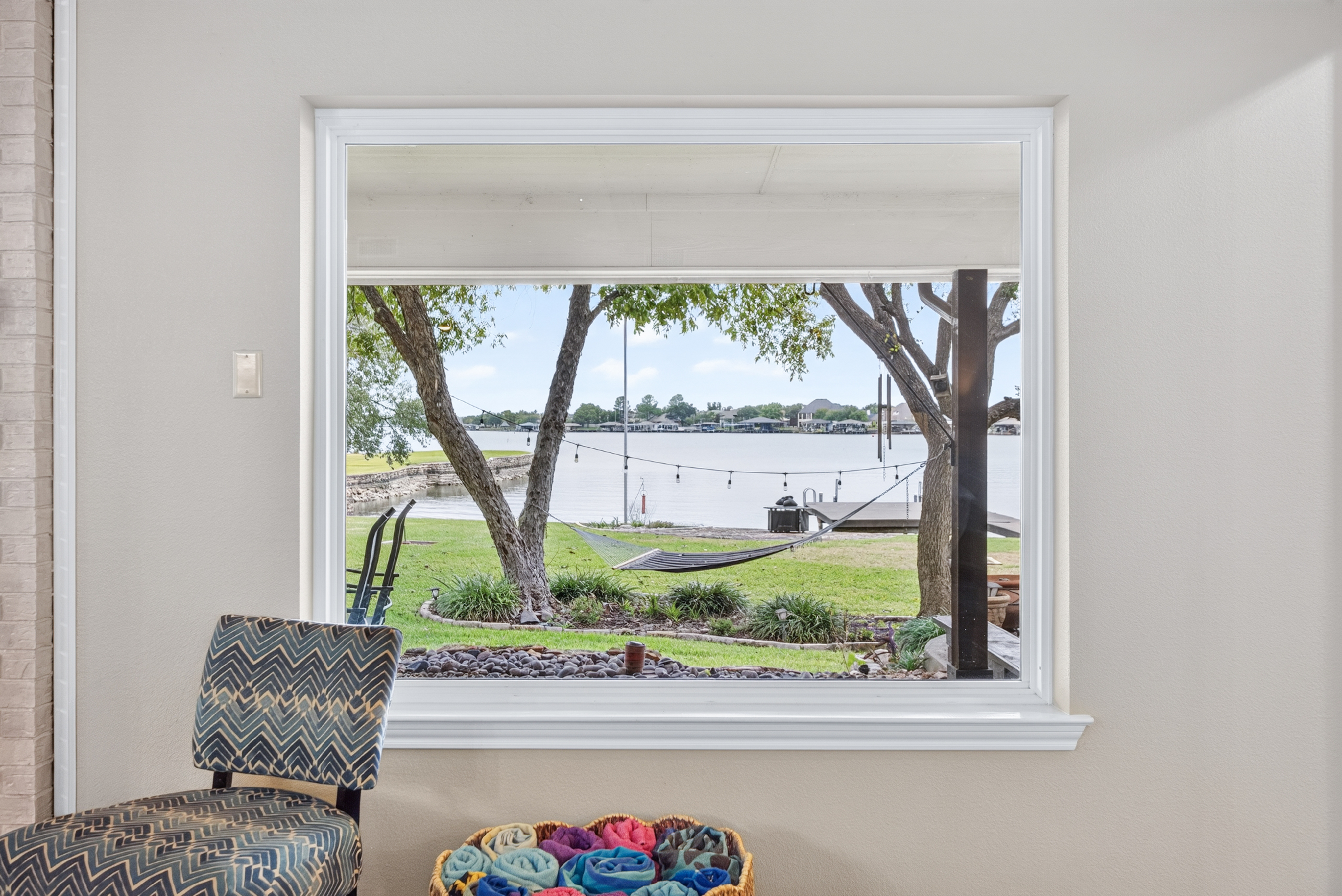 Large picture window with serene waterfront views and a backyard hammock