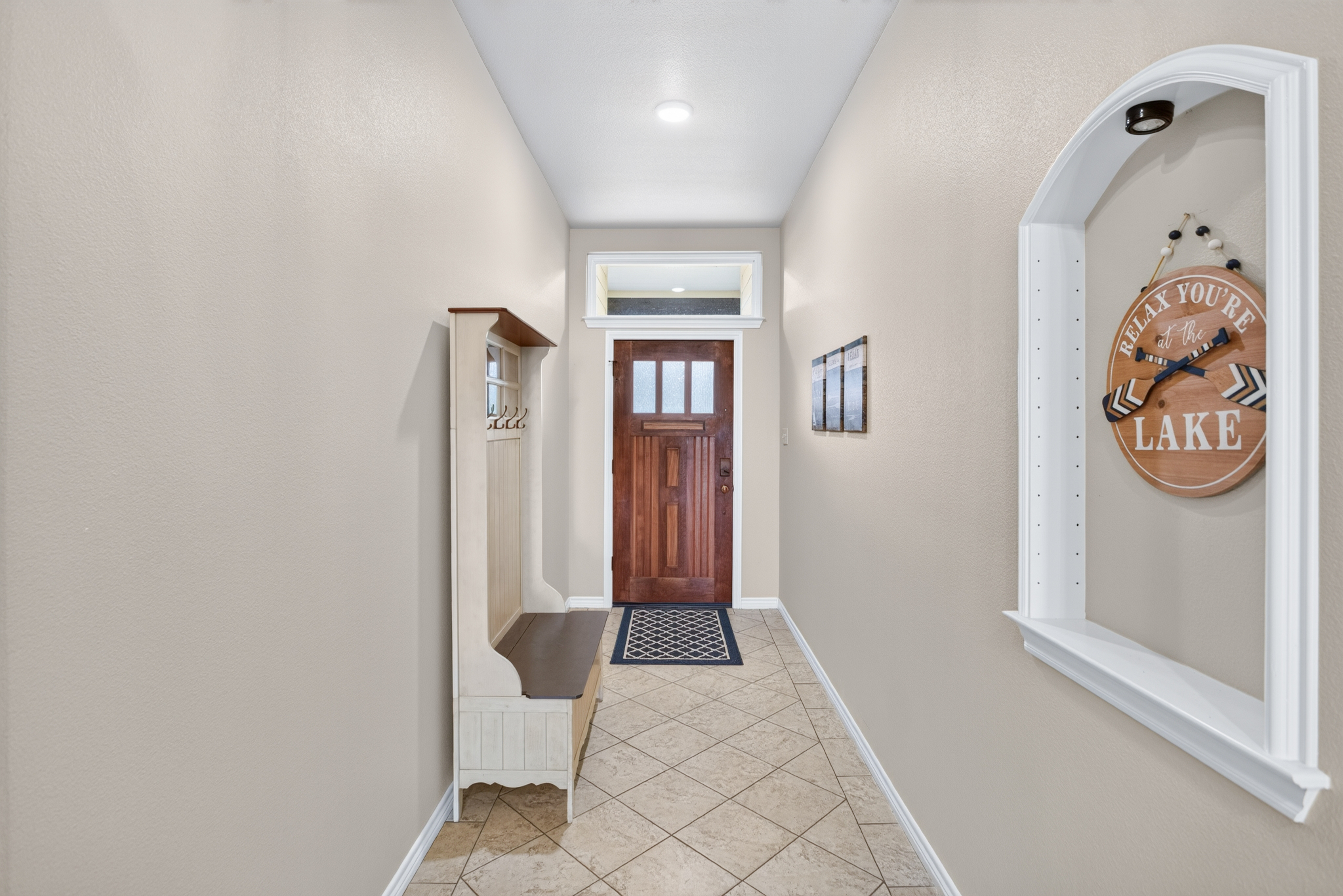 Bright entry hall with bench seating, tile floors, and lakehouse charm