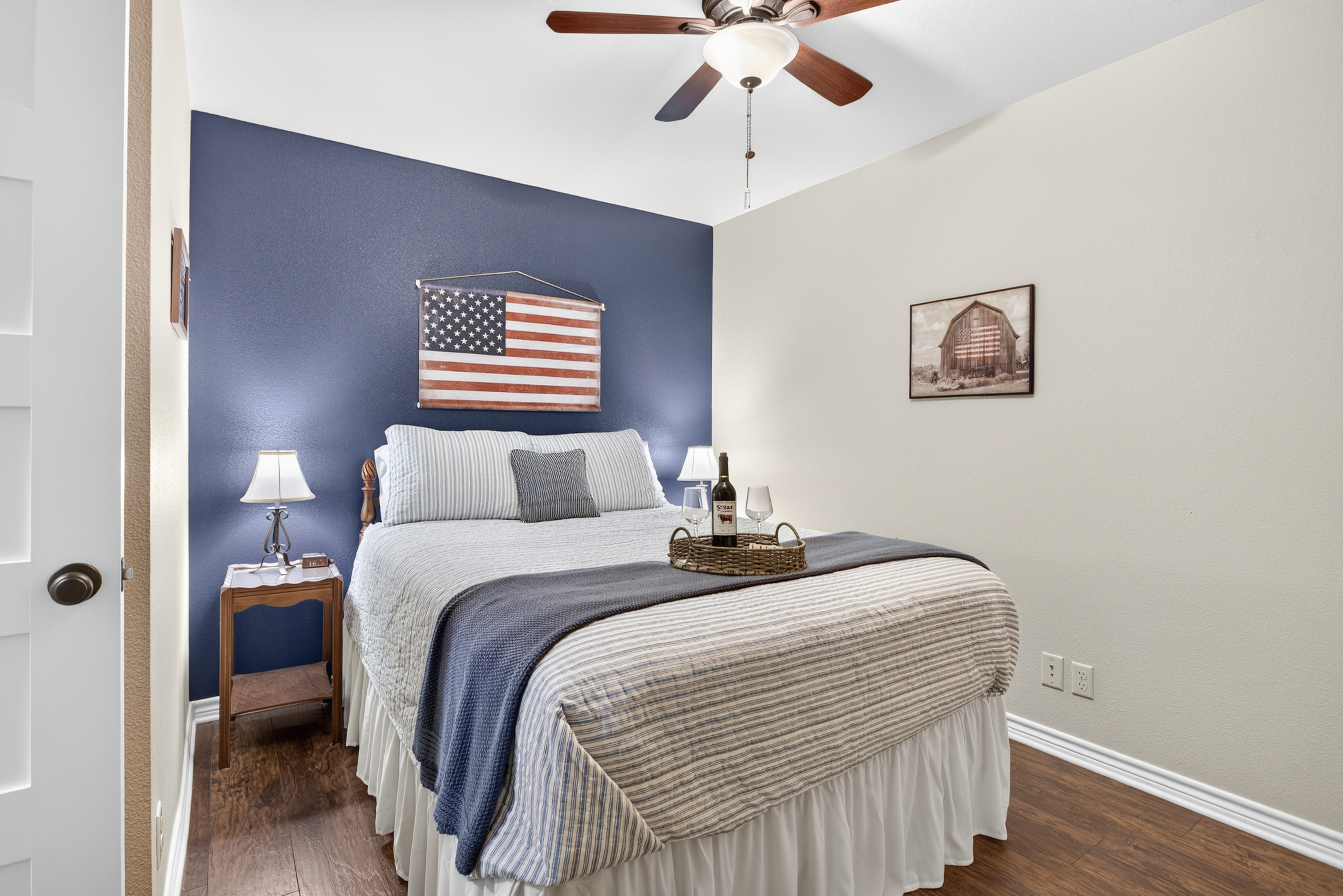 Cozy bedroom with navy accent wall, hardwood floors, and ceiling fan