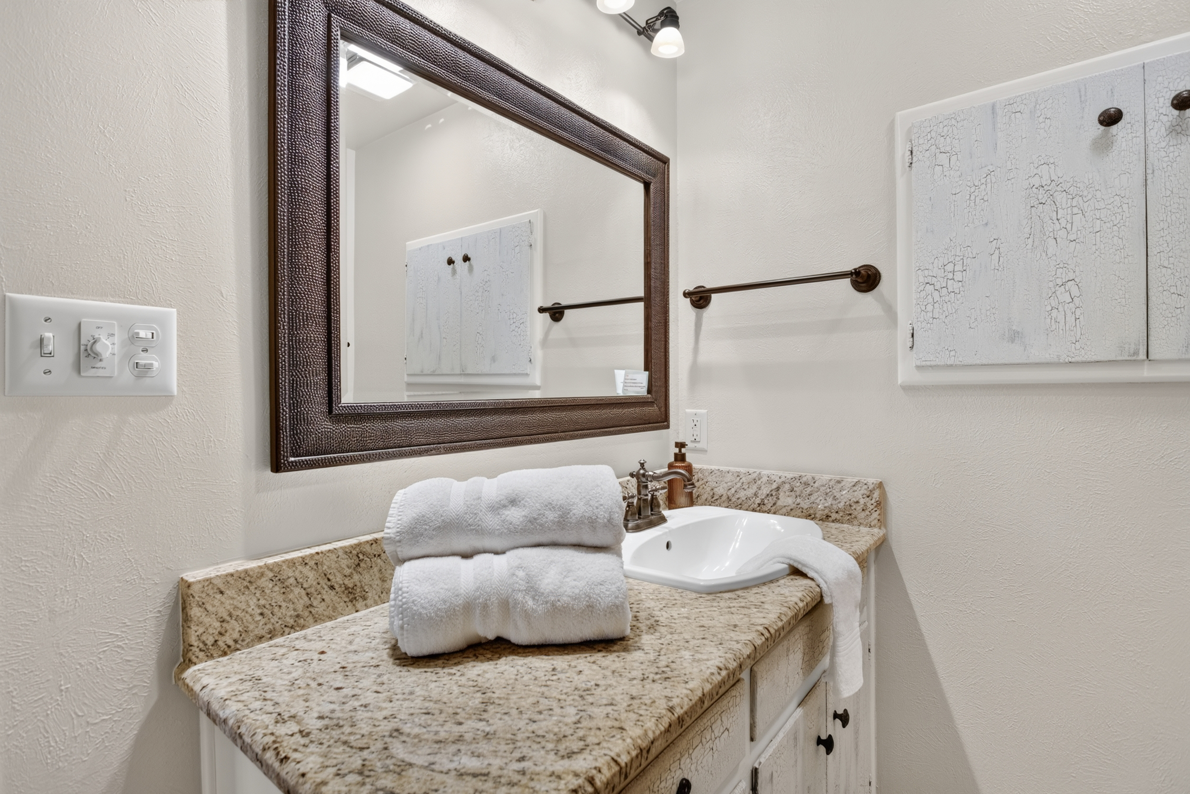 Bright bathroom vanity with granite counters and rustic charm