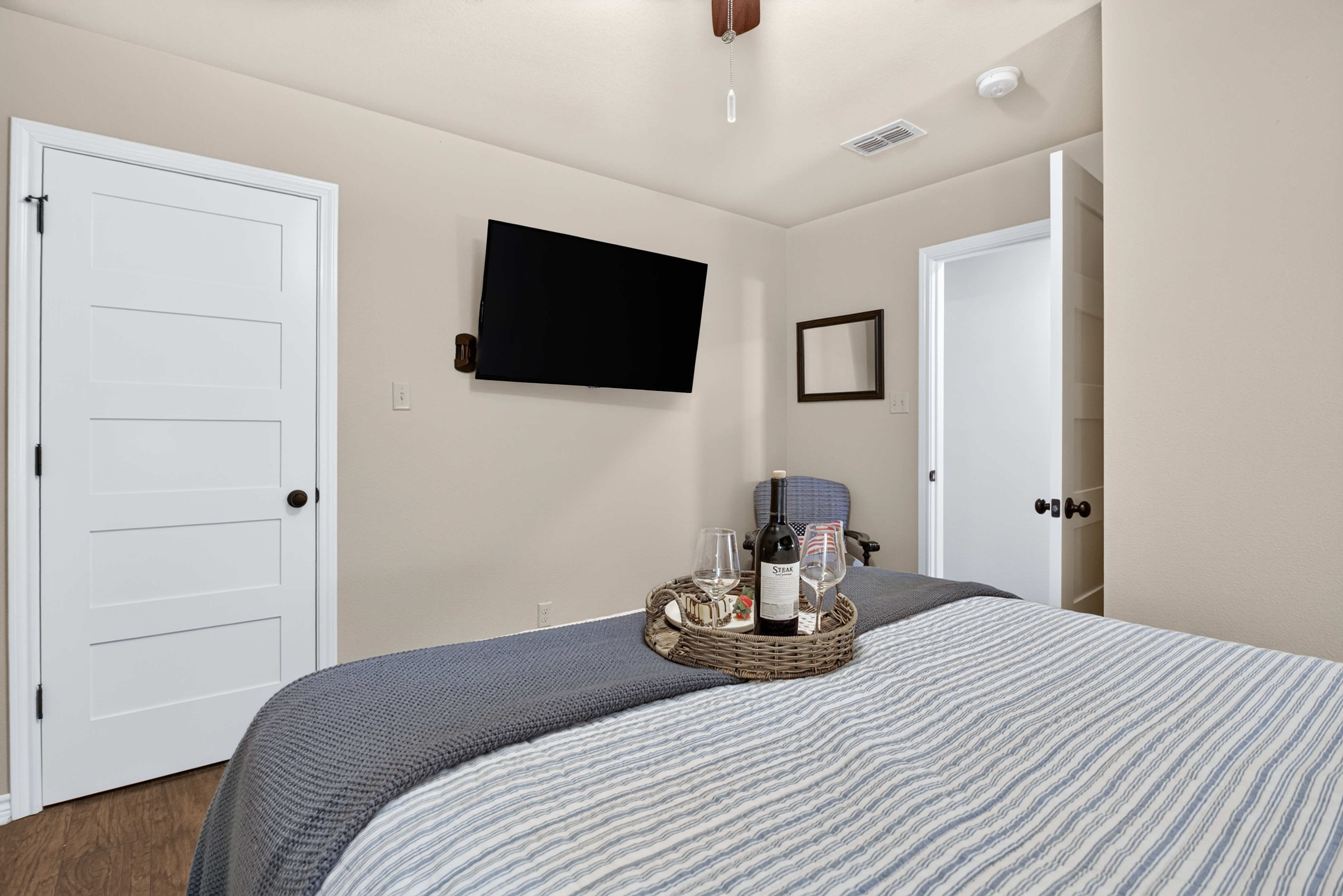 Cozy bedroom with wall-mounted TV and welcoming wine setup