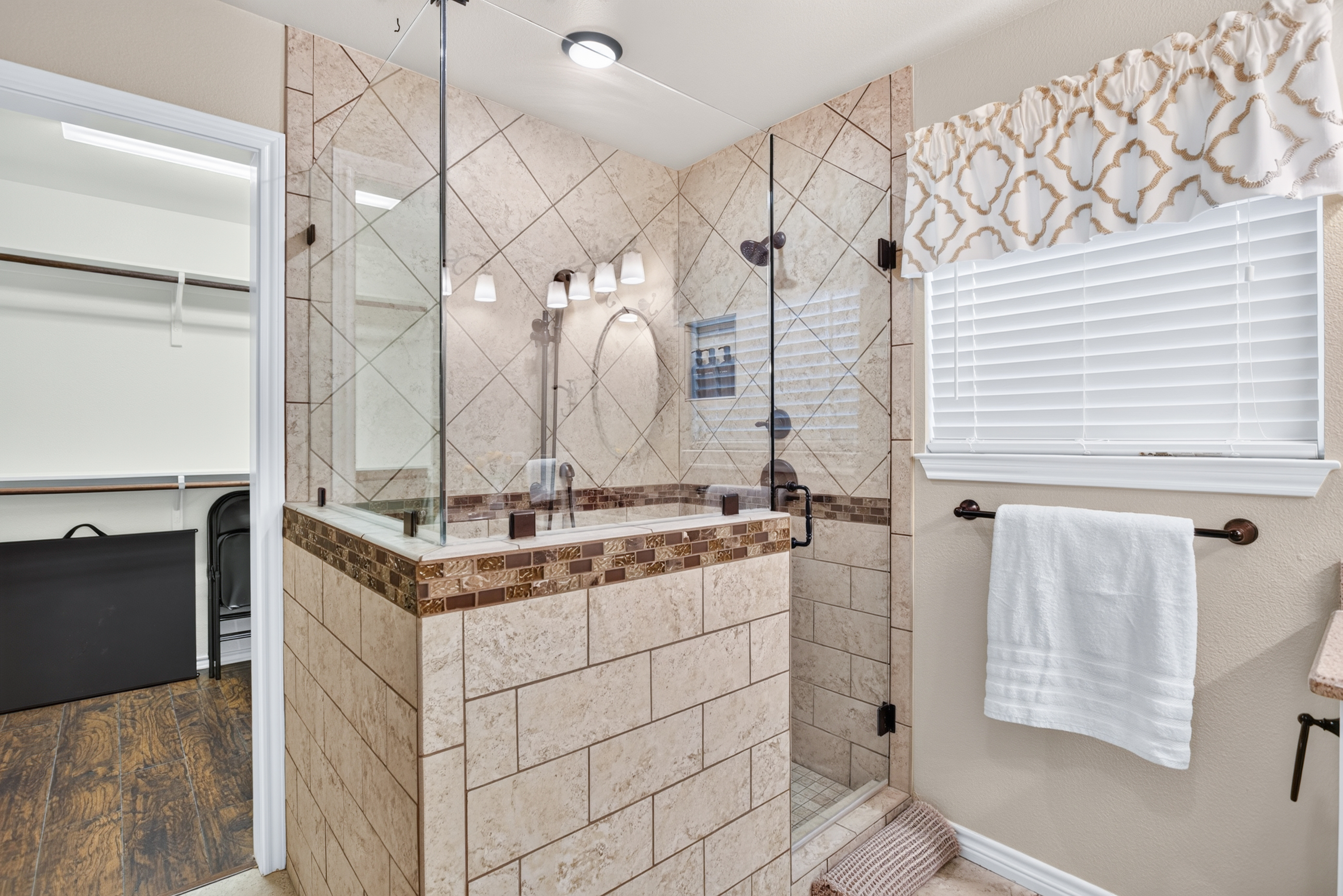 Bright tiled bath with glass walk-in shower and adjacent closet