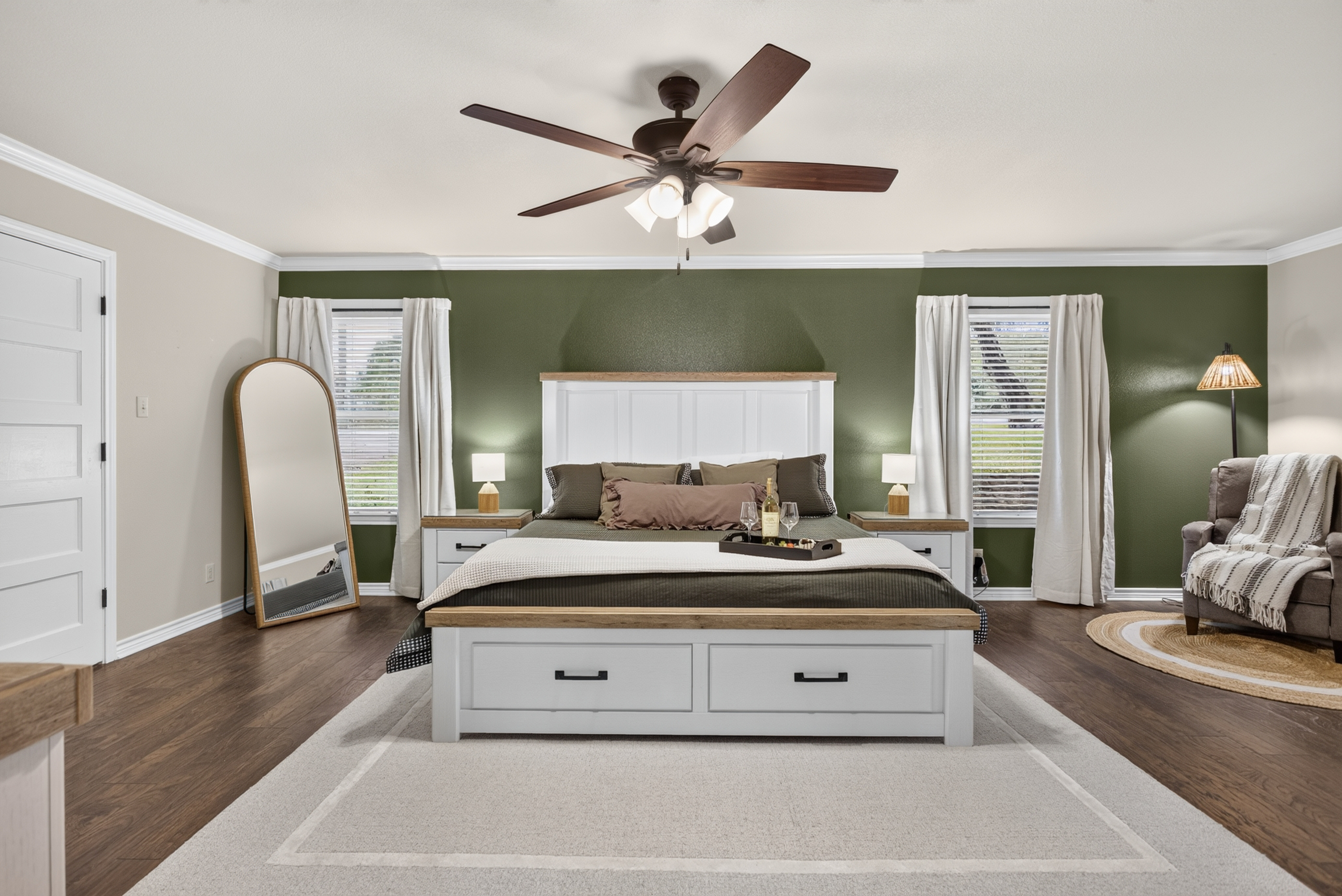 Spacious king bedroom with accent wall, seating nook, and natural light
