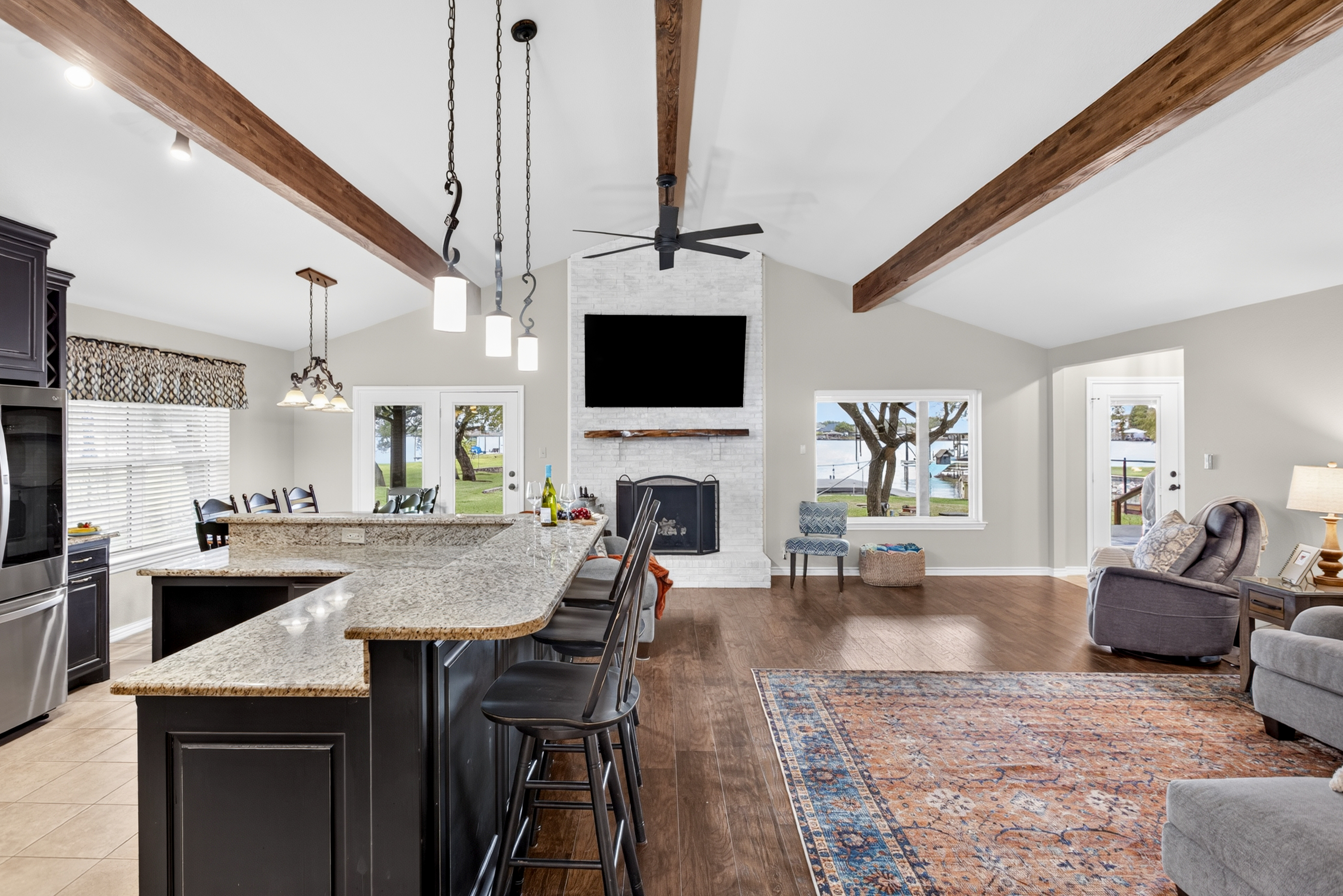 Open-concept great room with granite island, fireplace, and water views