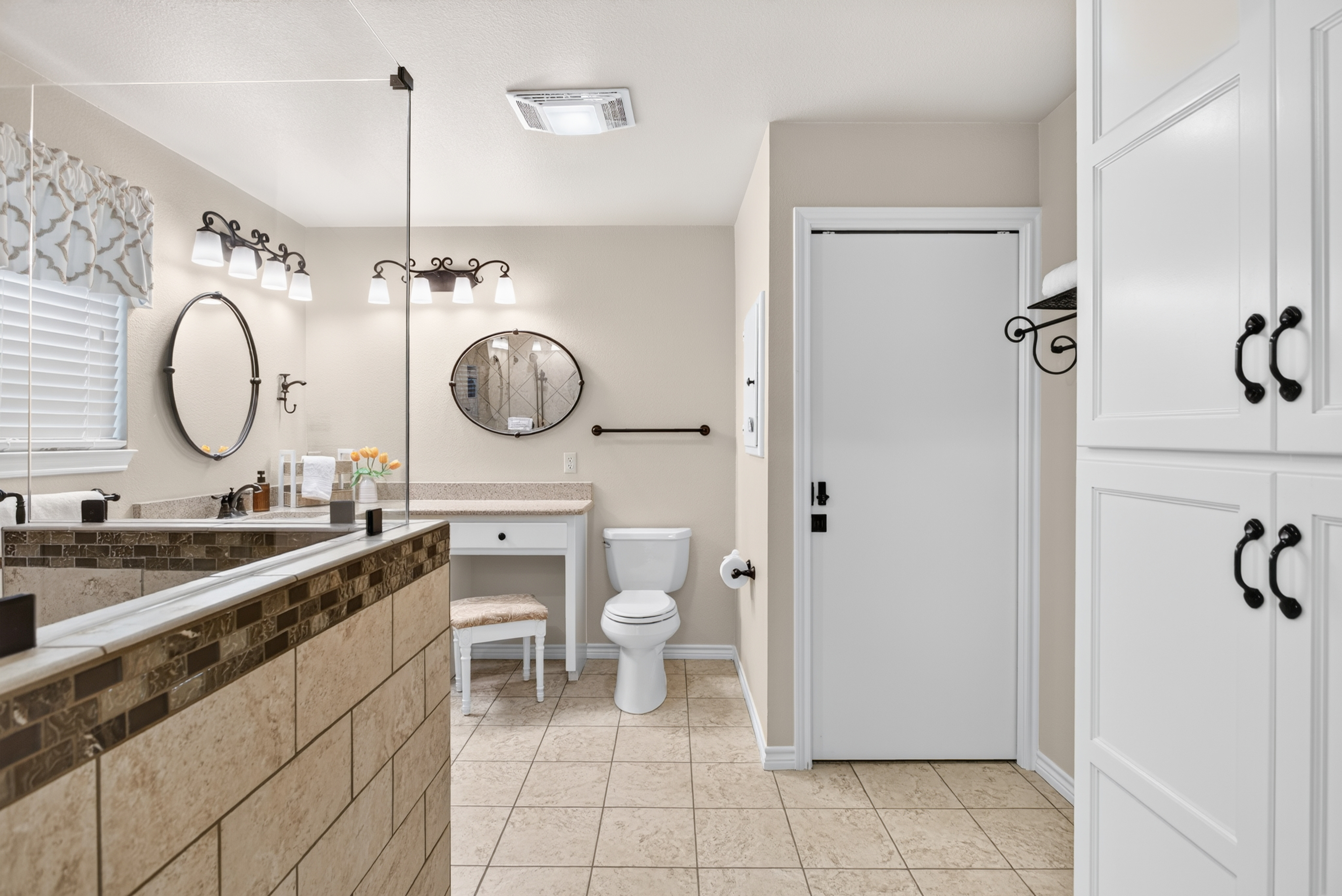 Spacious spa-style bathroom with tiled walk-in shower and ample storage