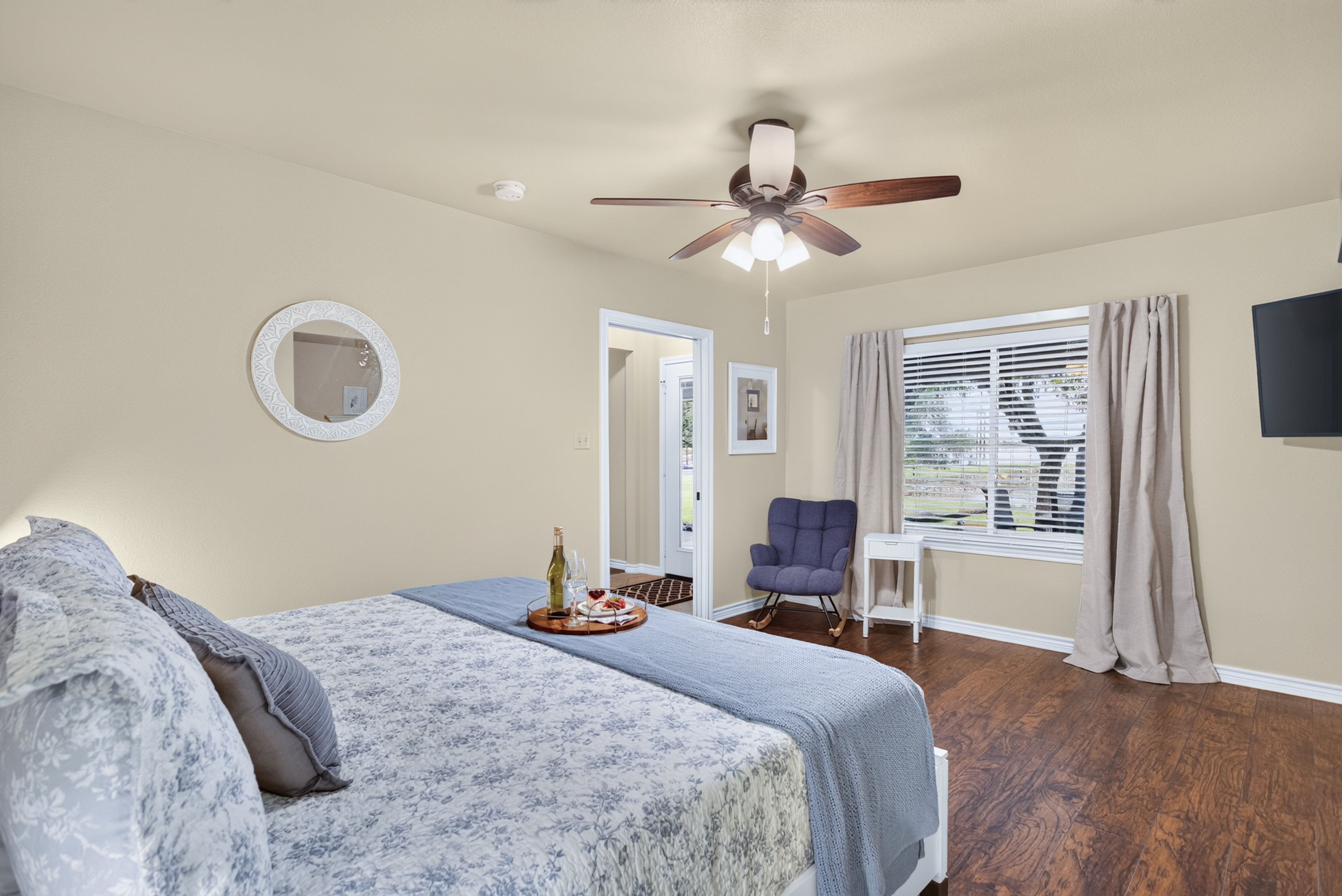 Bright, spacious bedroom with cozy seating, TV, and natural light