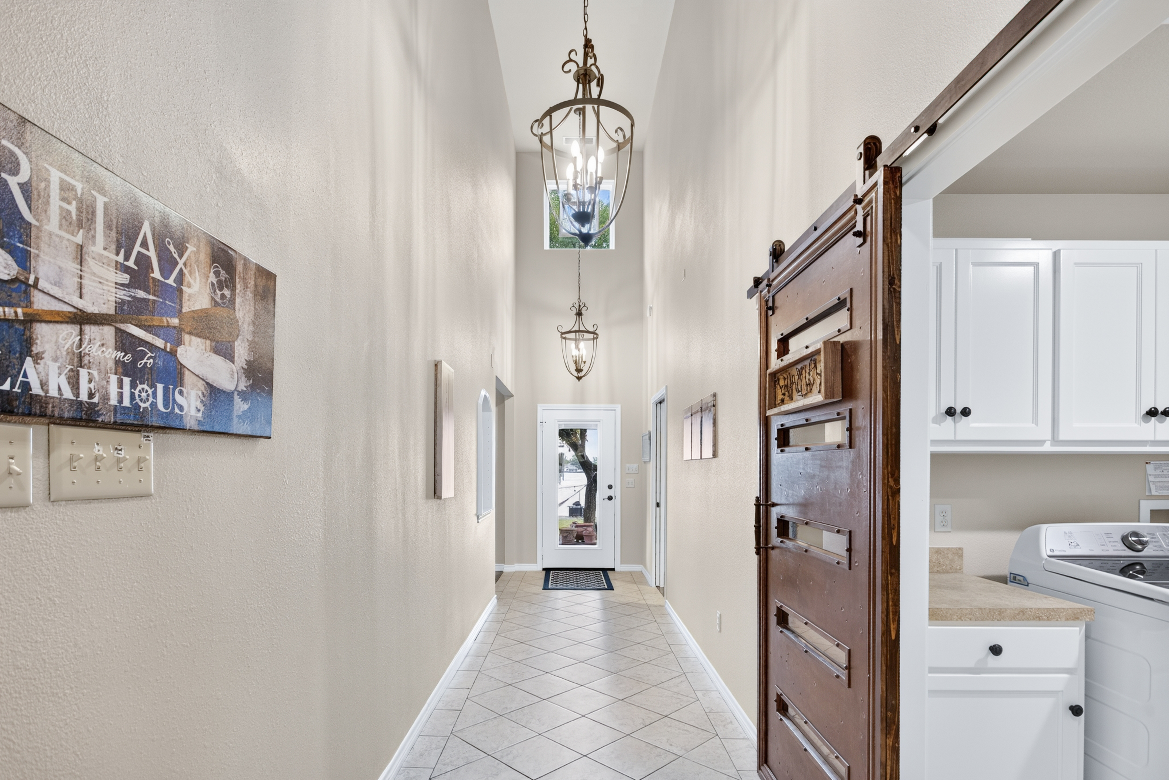 Bright entry hall with soaring ceilings, barn door, and convenient laundry